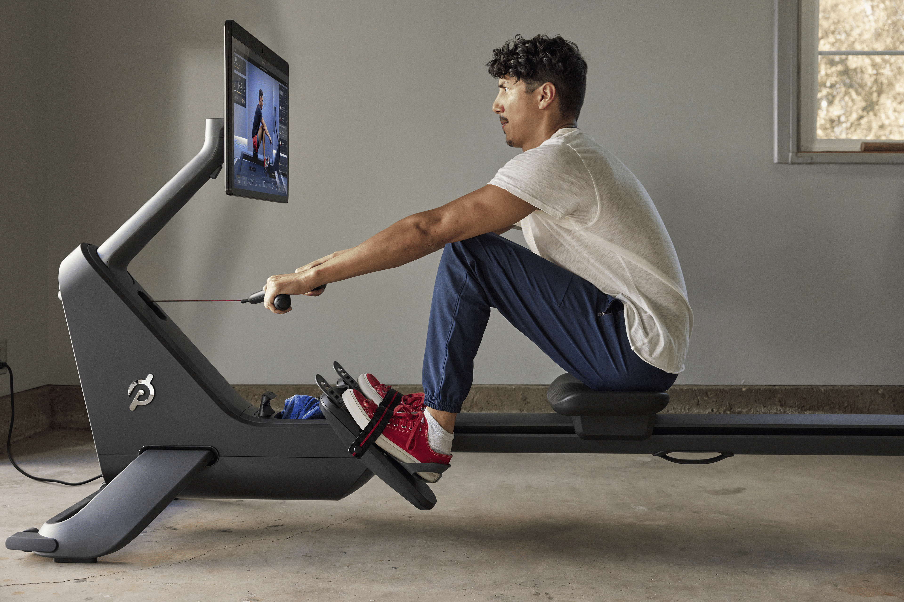 Man does a Peloton Row workout at home
