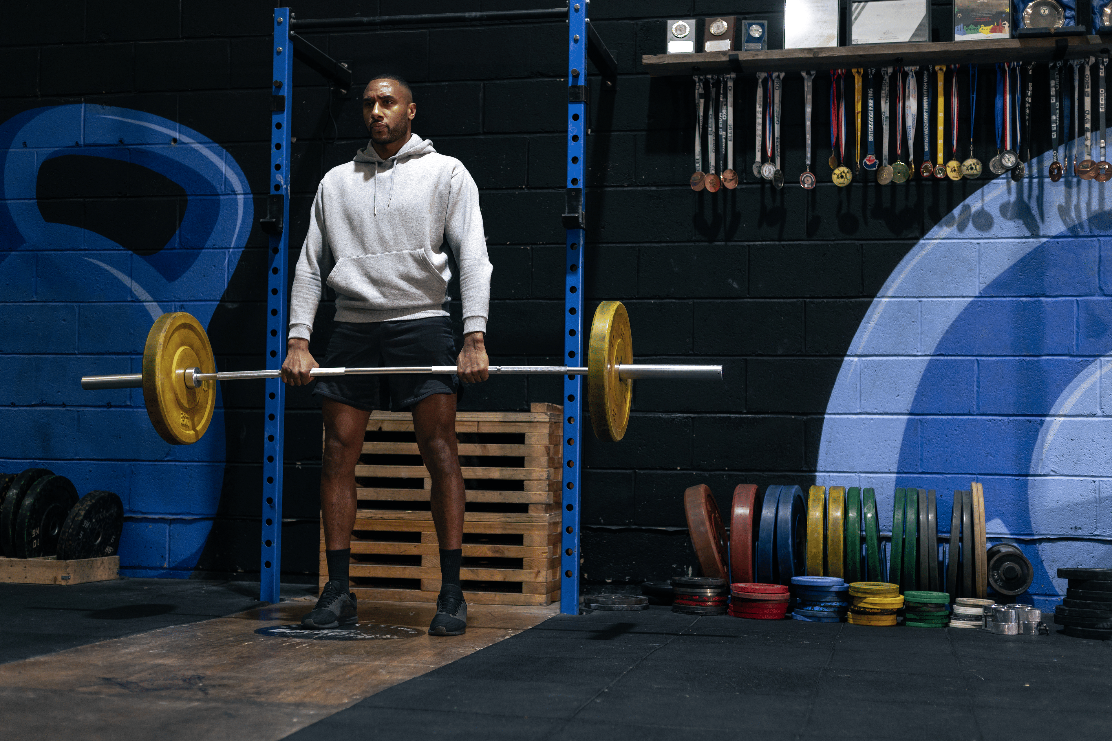 Man in a gym holding a loaded barbell about to perform bent-over barbell rows with proper form