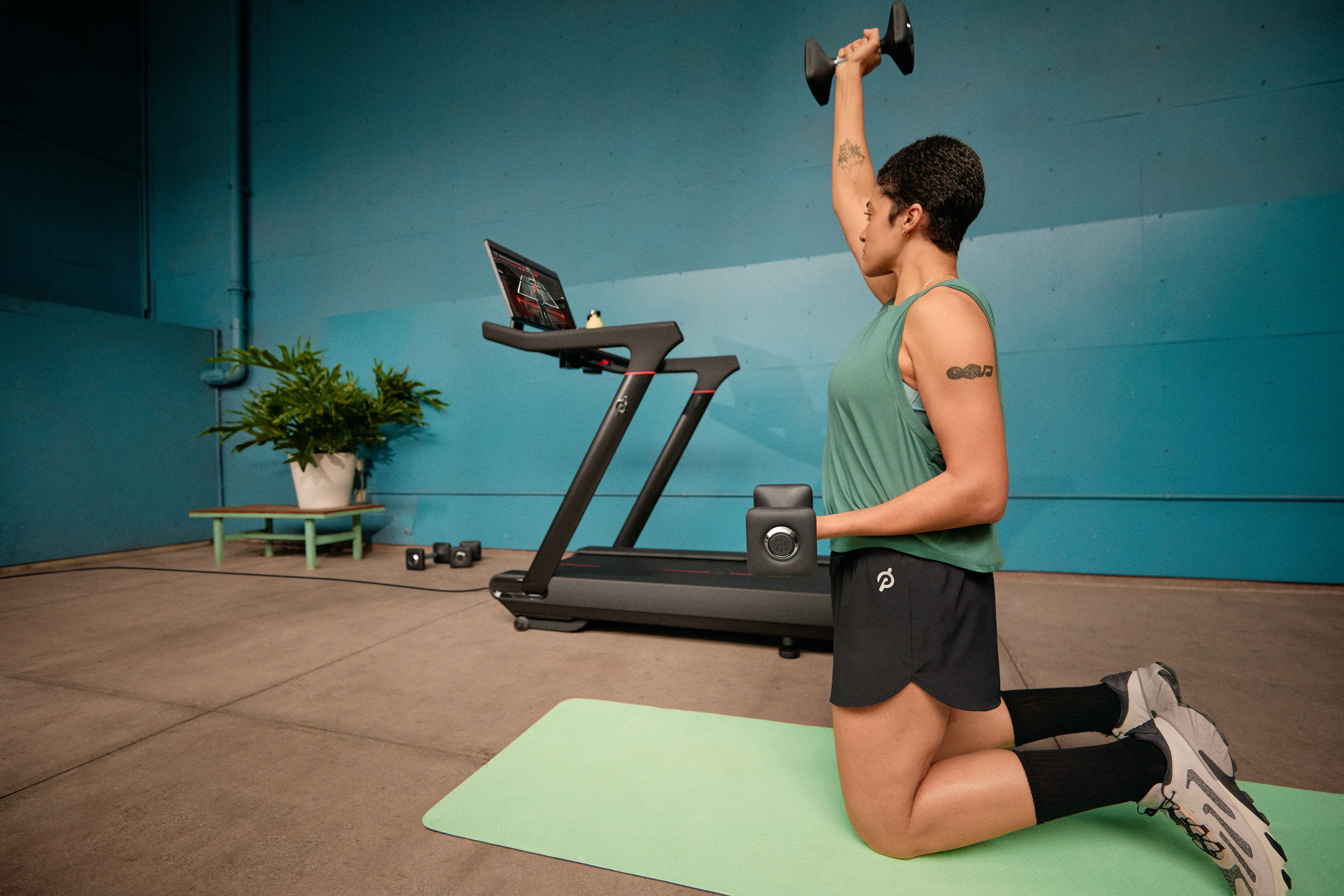 A woman engages in hybrid training while doing a Peloton Tread Bootcamp workout class. 