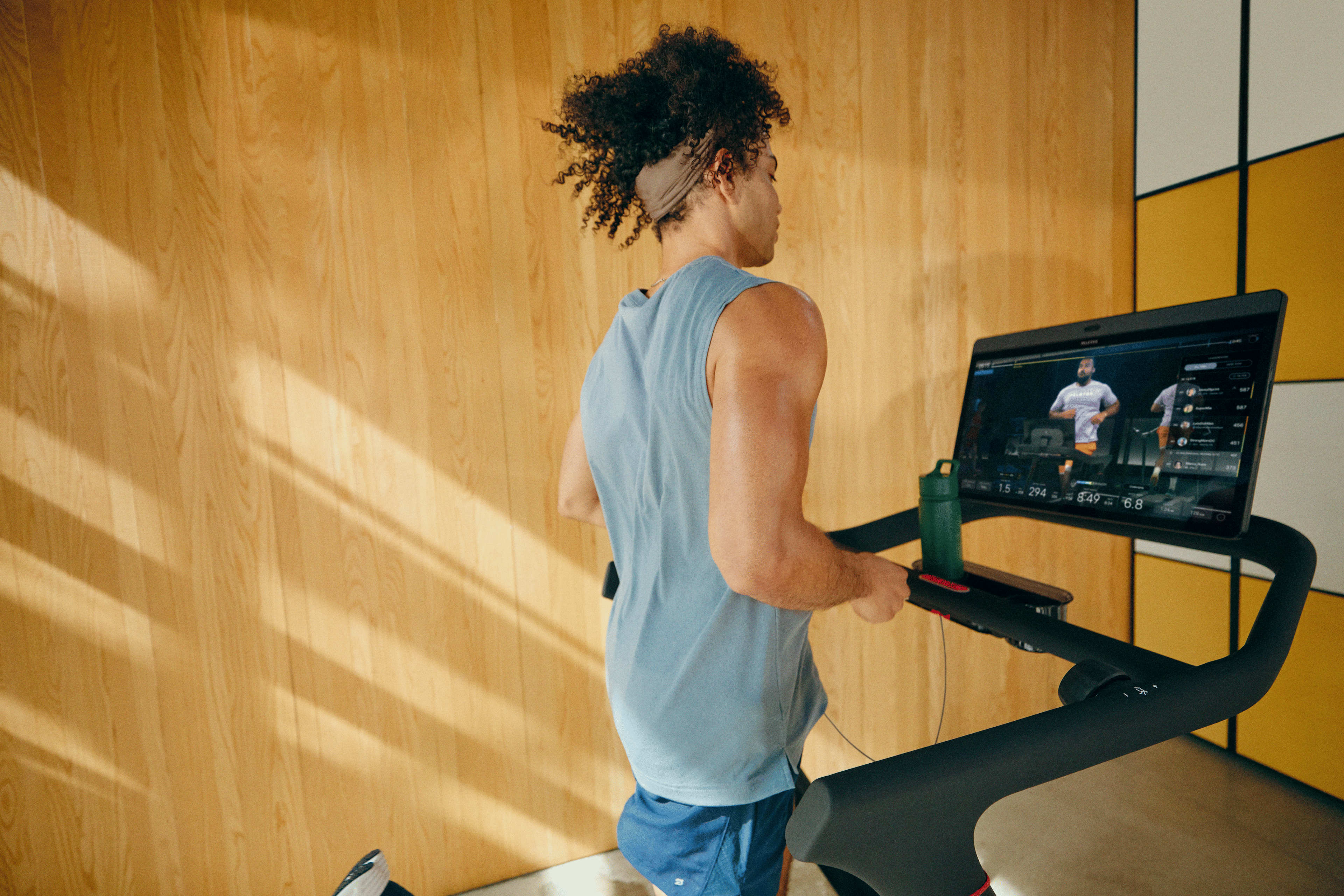 Man running on a Peloton treadmill doing a guided running workout.