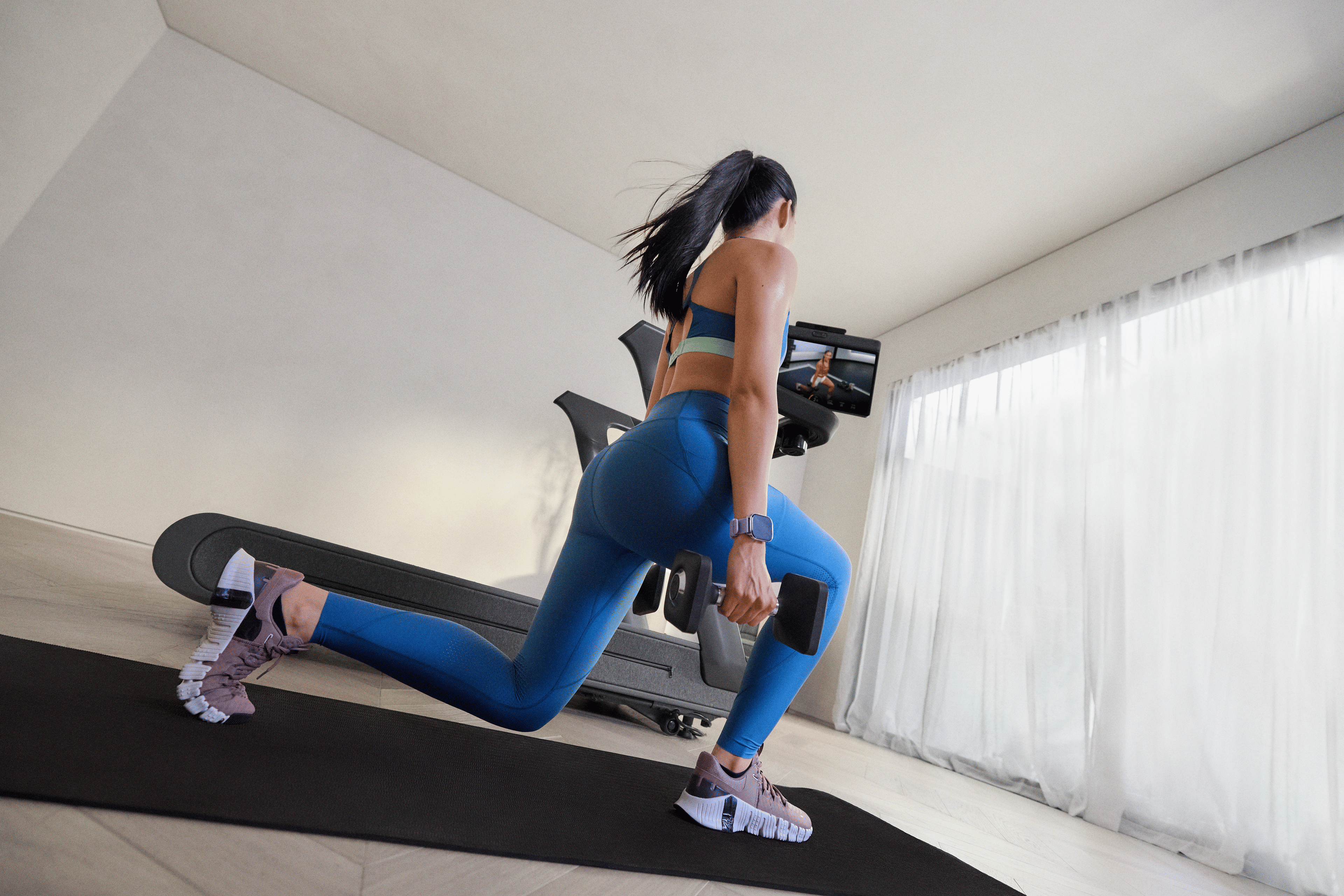 Woman doing a cross training workout for runners with dumbbells using a Peloton Cross Training Series treadmill.