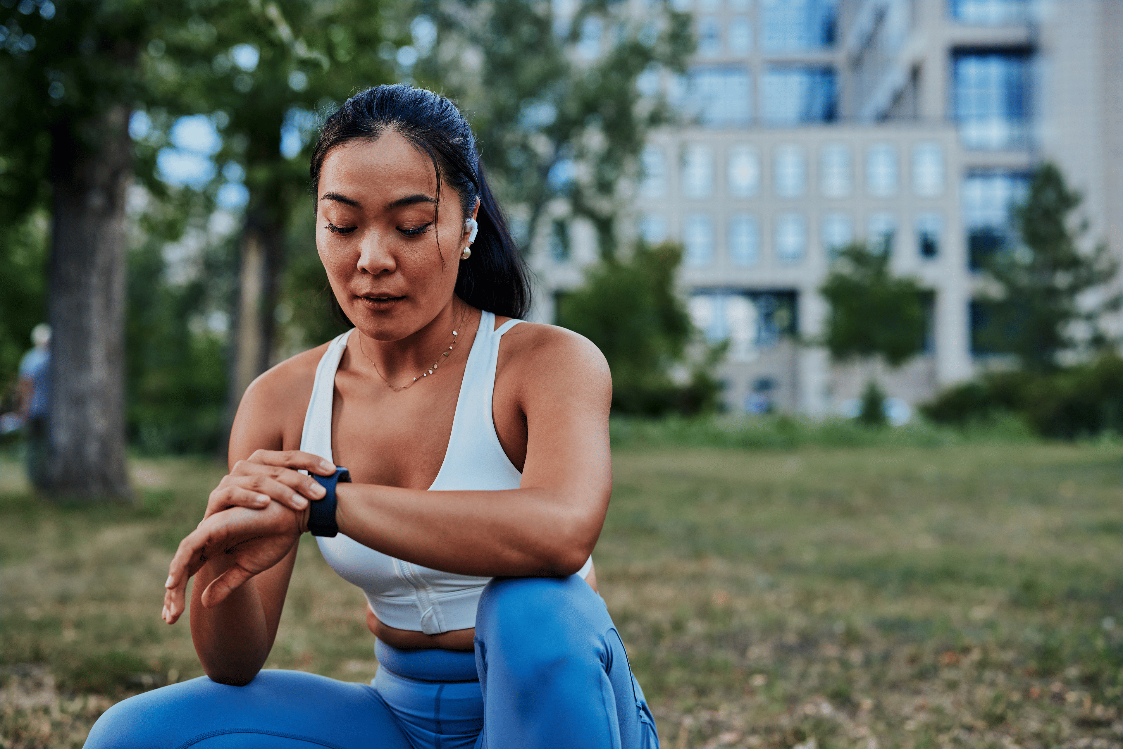 Woman resting on a step outside after a run and looking at her watch wondering how many miles to run per week.