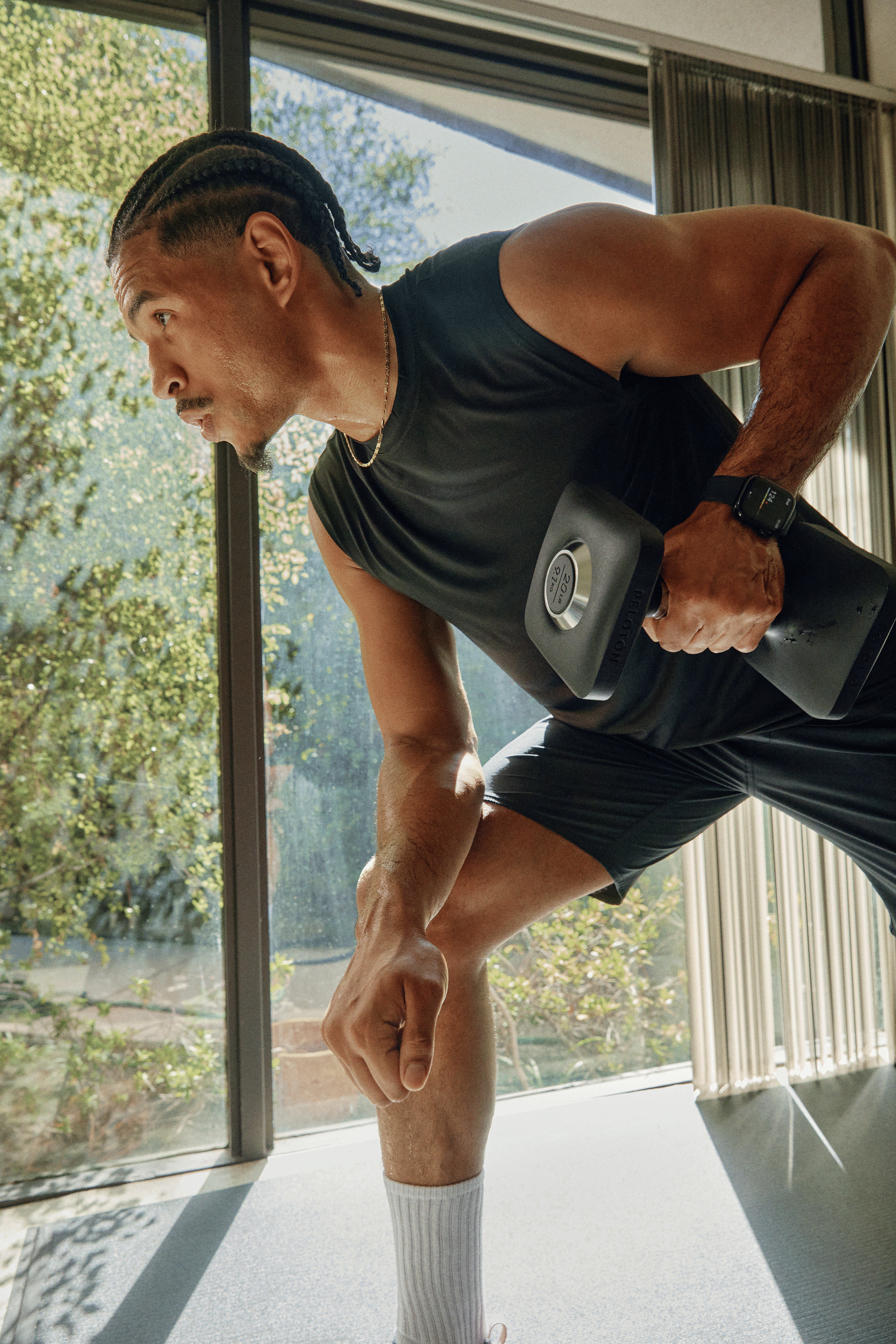 Man rowing a dumbbell during a Peloton strength training workout.
