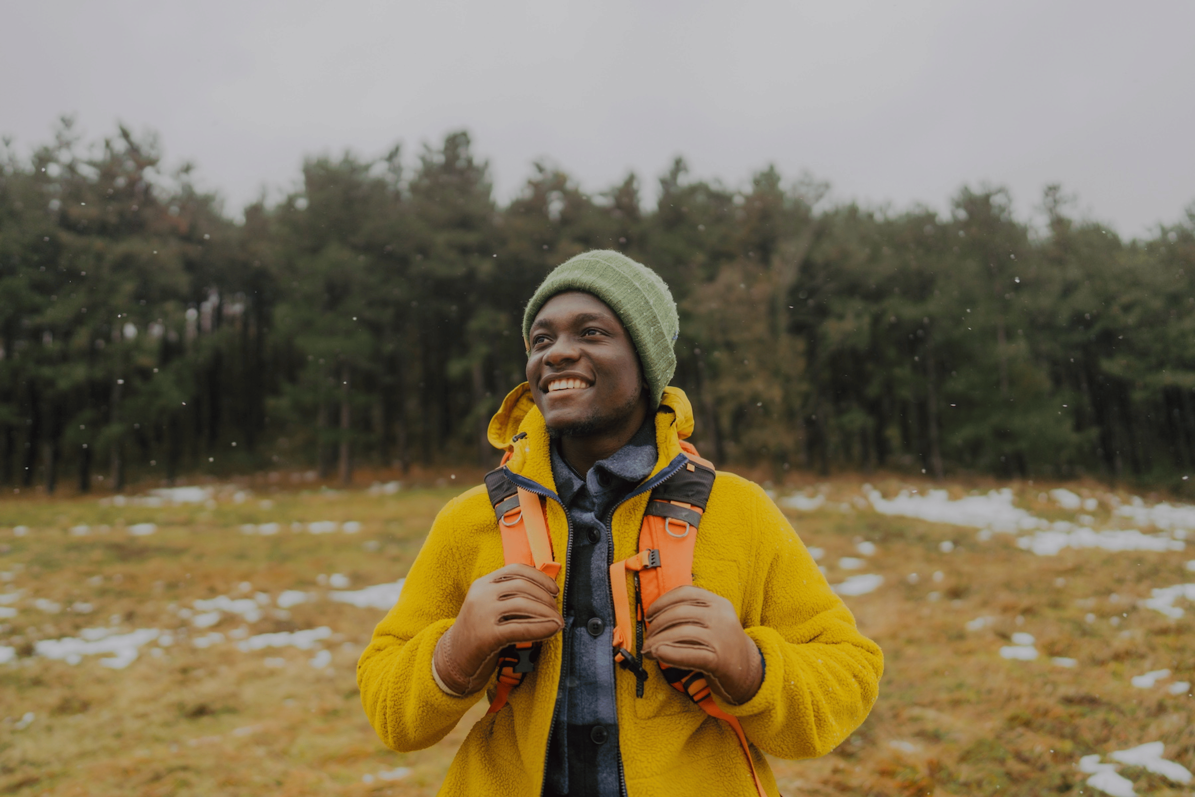 A happy man outside for a hike on a snowy day, practicing self-care.