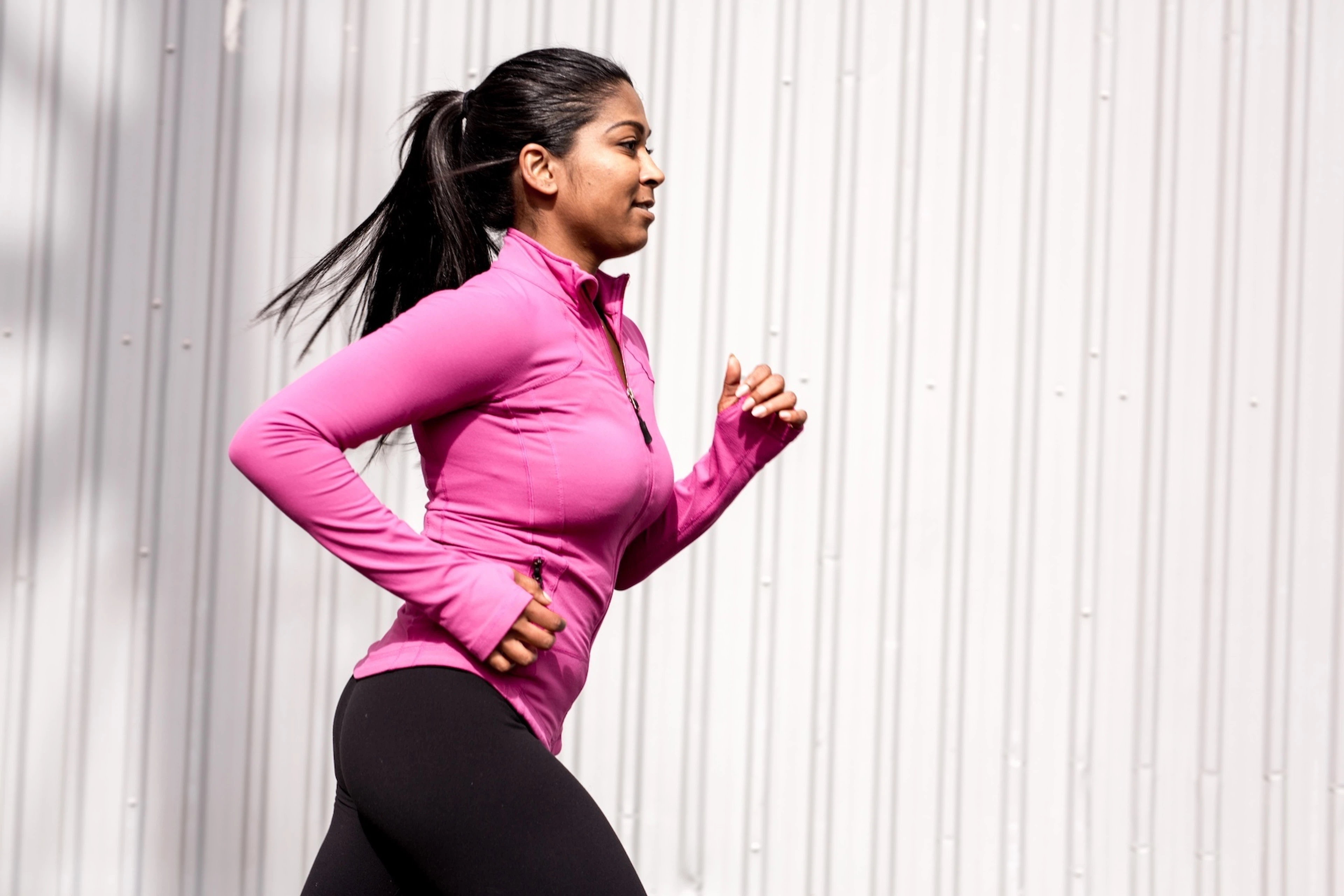A side view of a woman running outside.