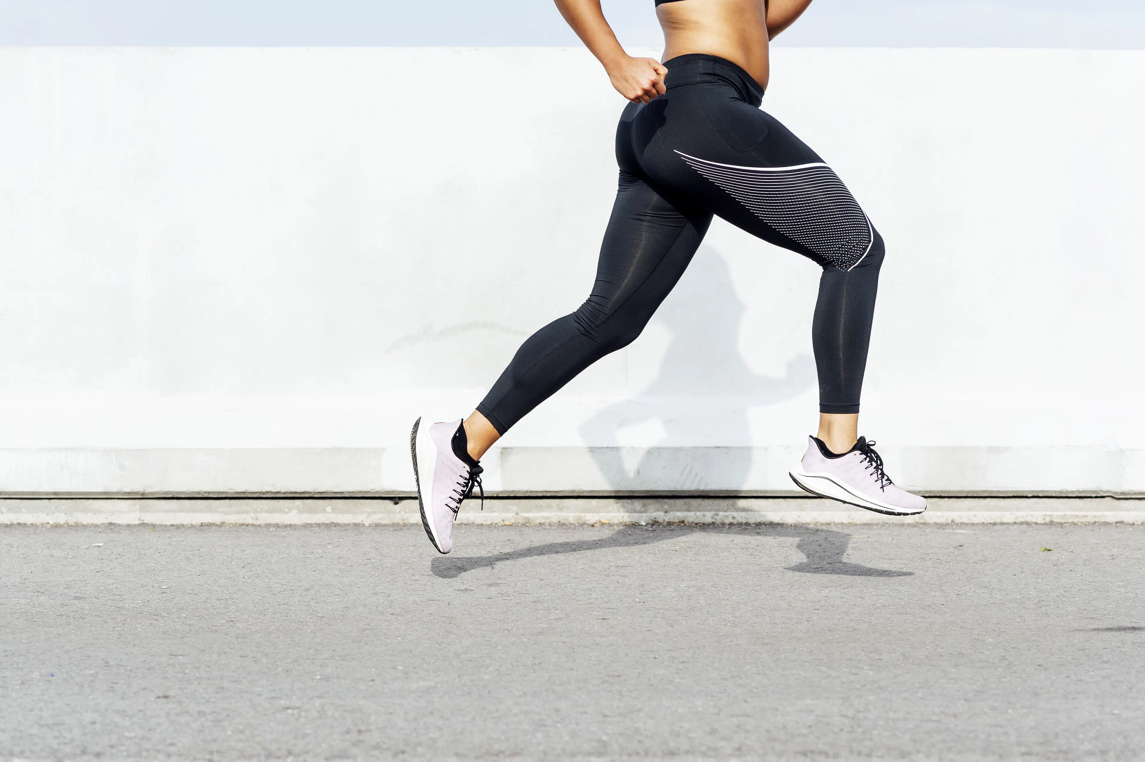 Close up shot of a woman's legs while she's running strides outside.