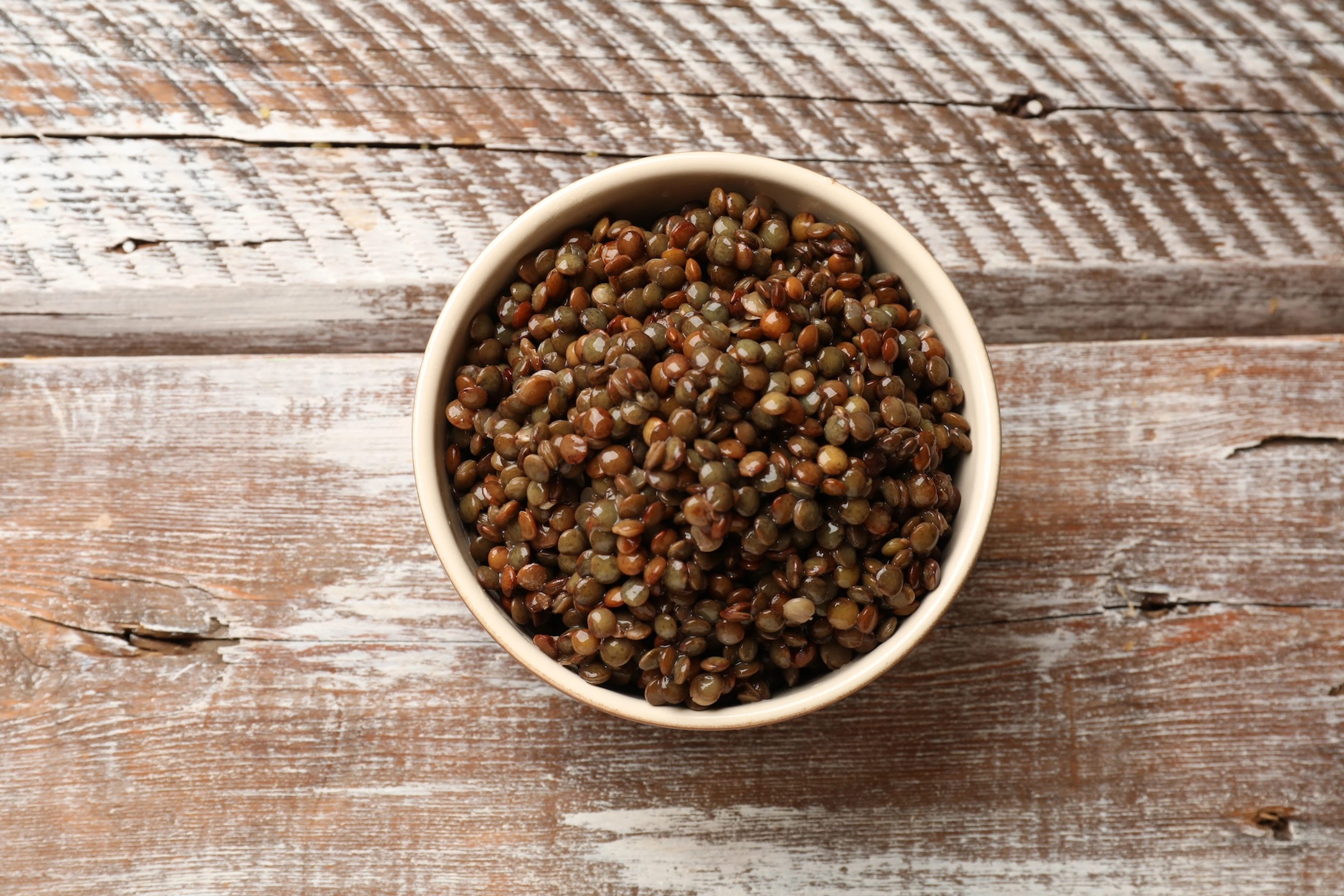 A bowl of lentils resting on a table.