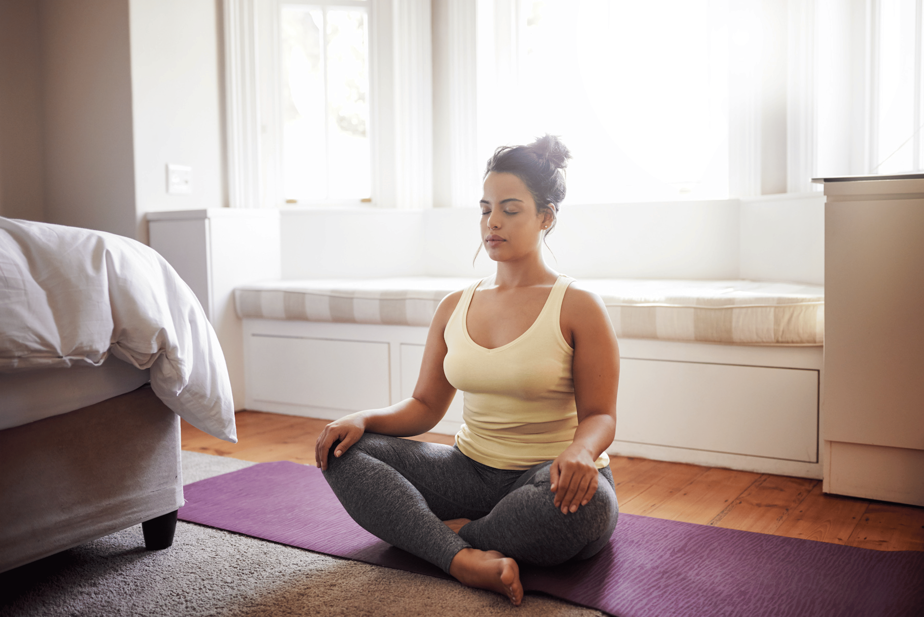 A woman sitting in her room practicing meditation before exercise.
