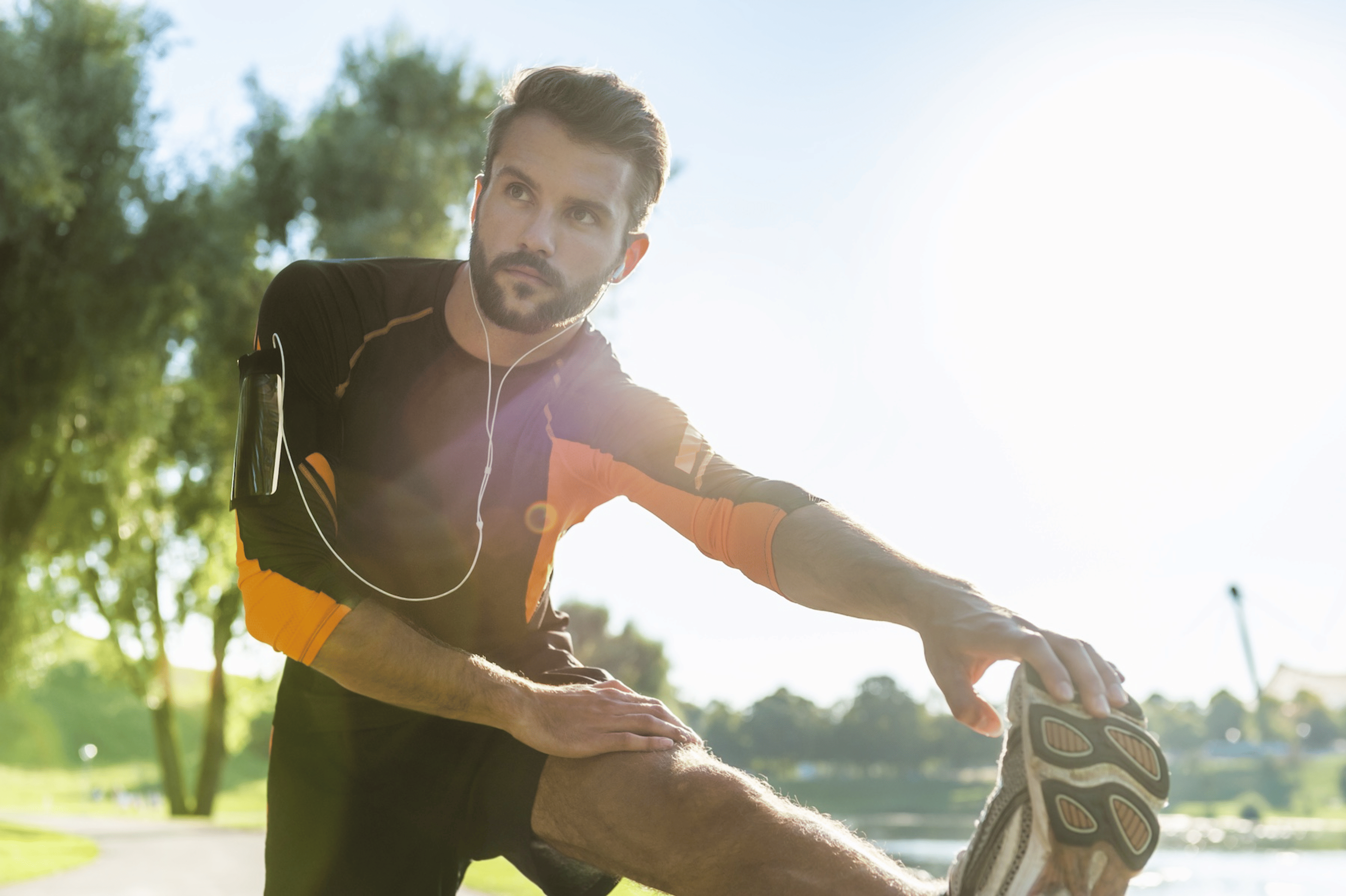 A man stretching his leg outdoors before he works out twice a day.