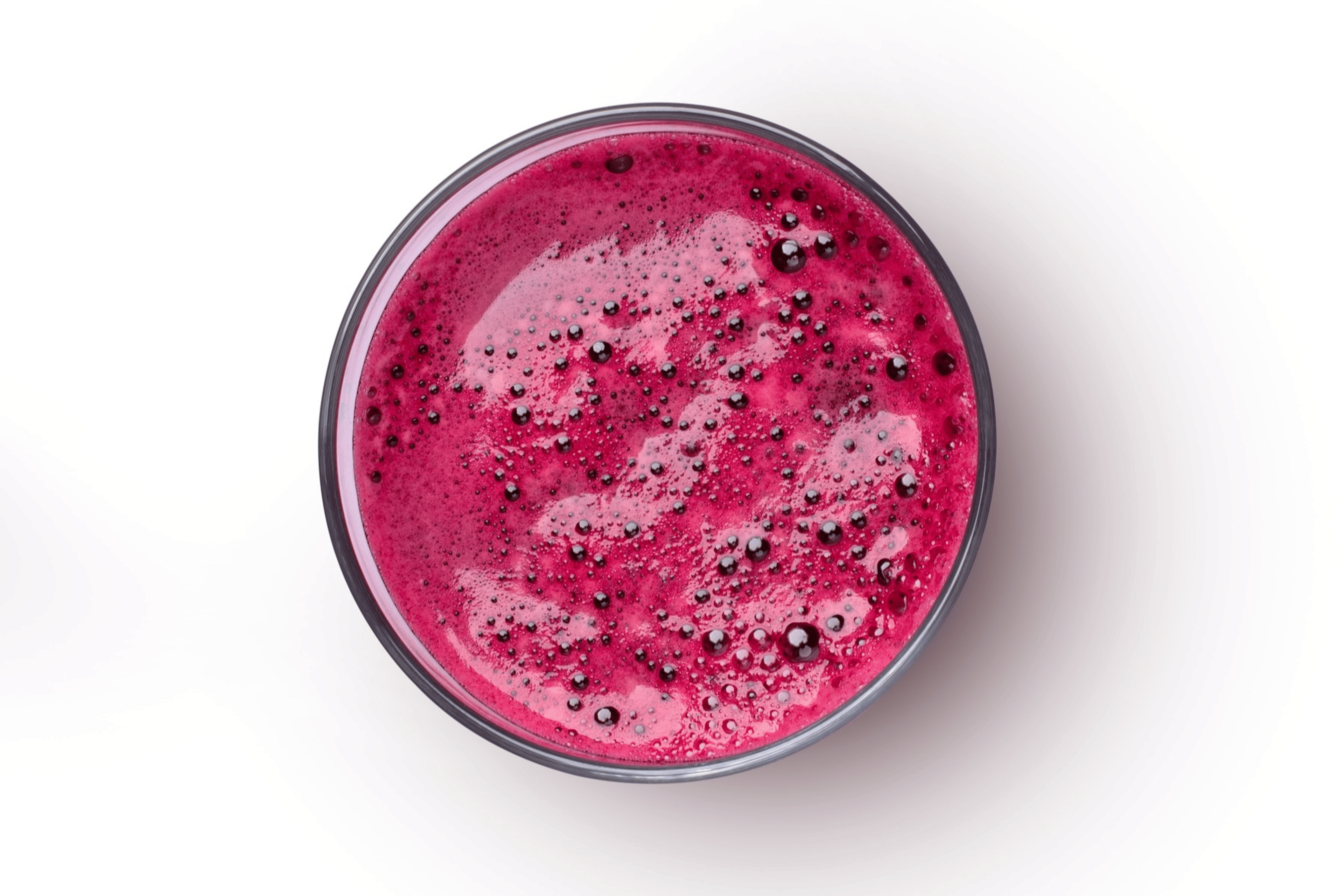 A bird's-eye view of a glass of beet juice on a white background.