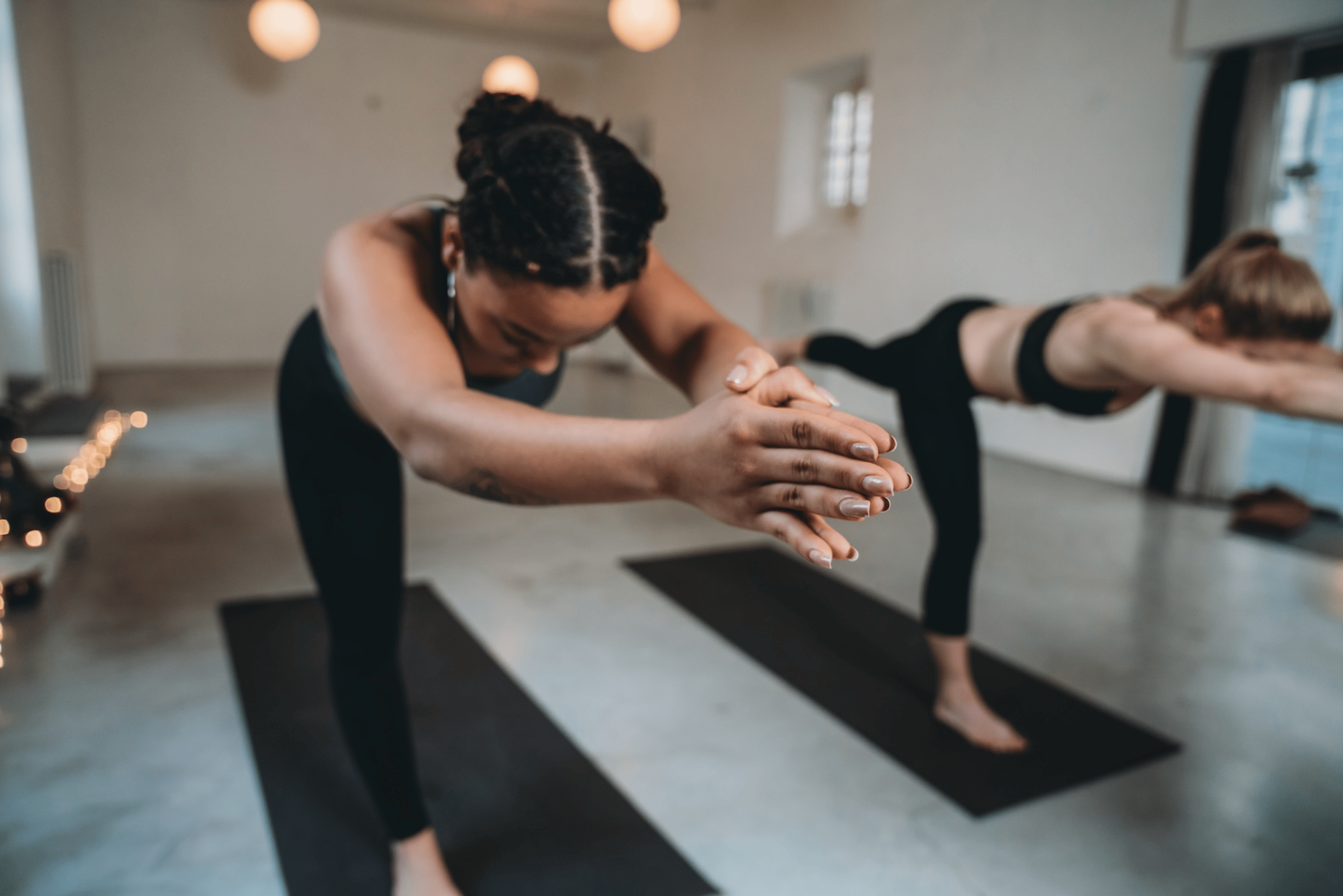 Two women doing a yoga class together, both in Warrior 3.