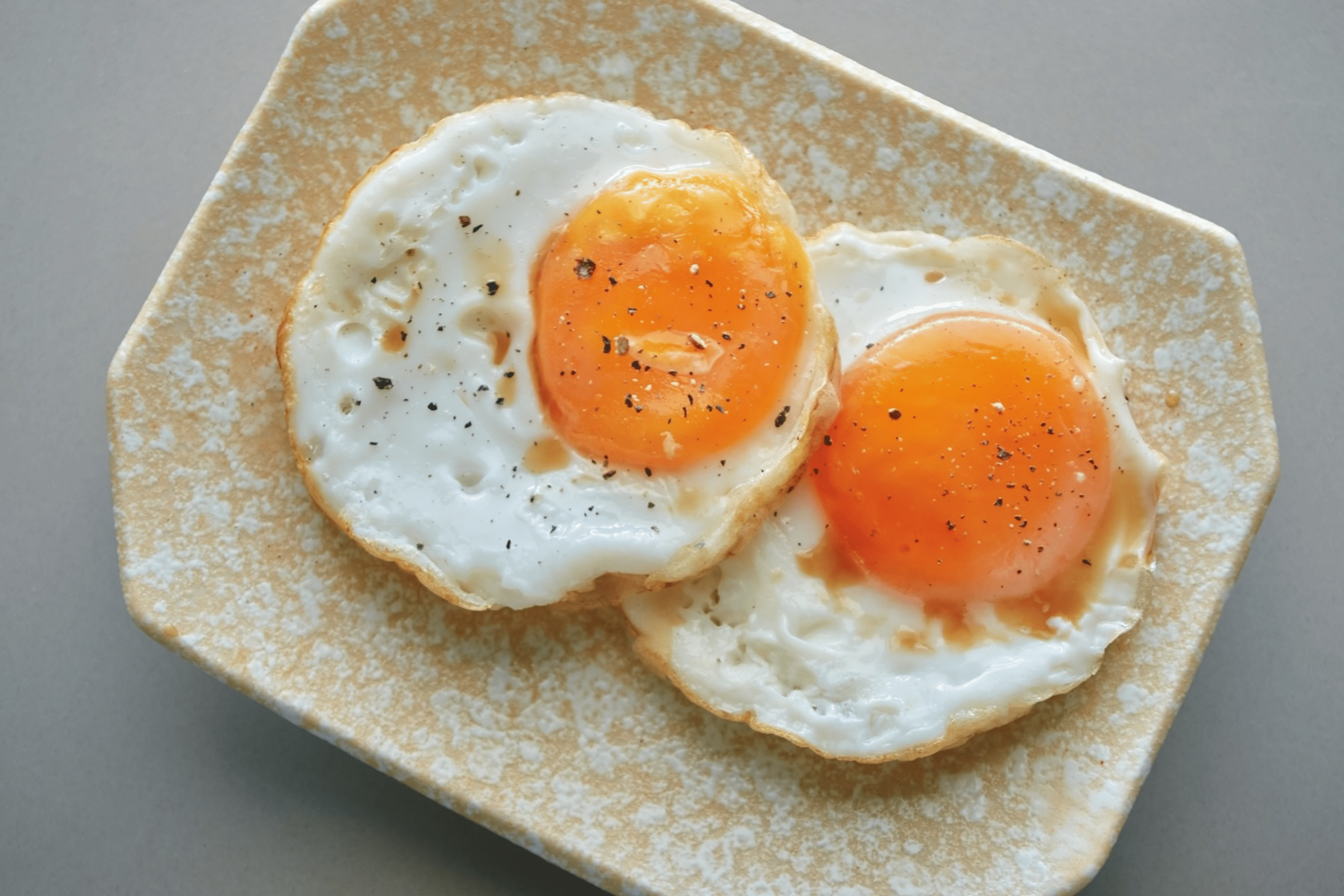Two fried eggs on a ceramic plate. Eggs are great non-meat protein sources.