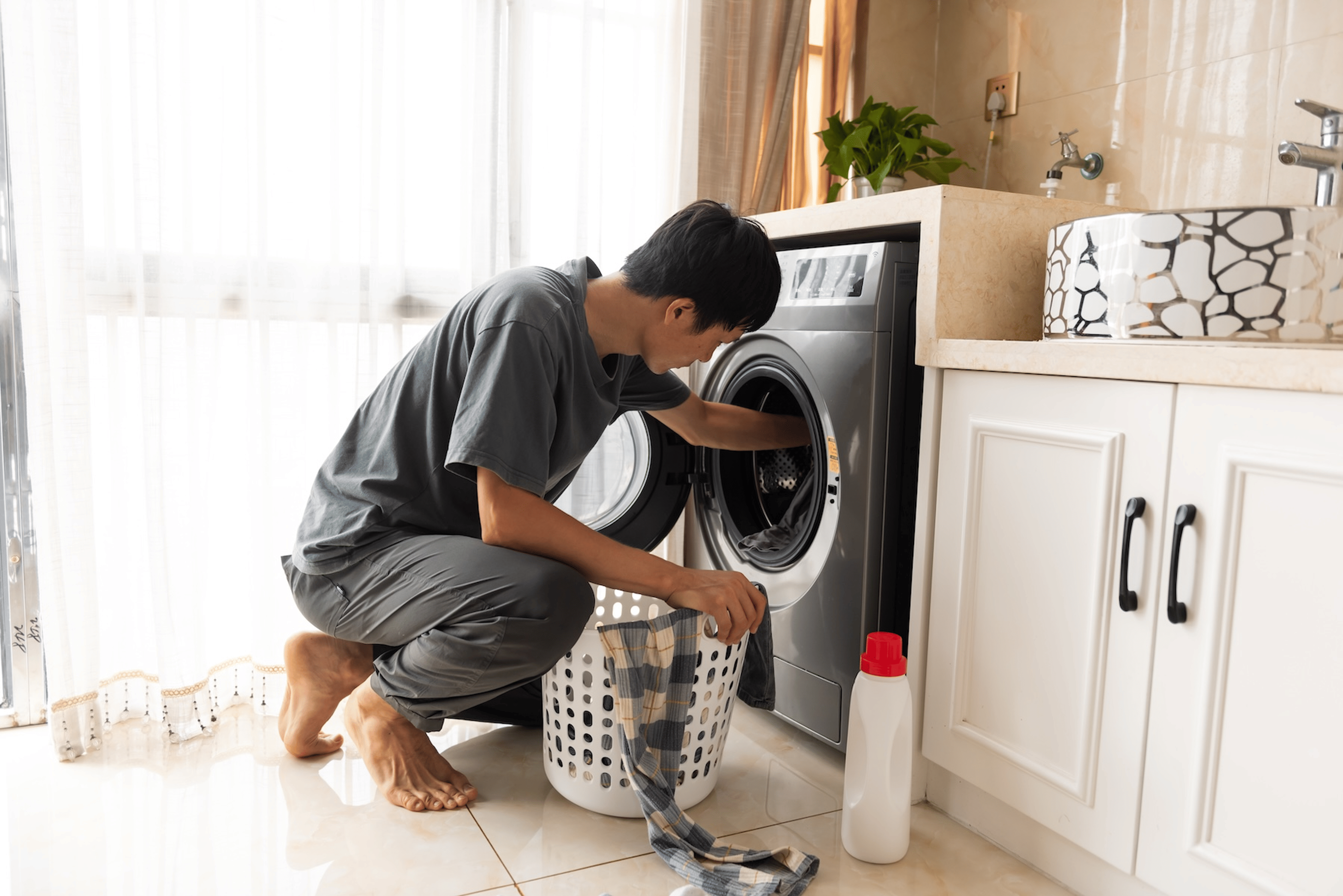A man loading clothes into a washing machine at home as part of his Sunday reset routine.
