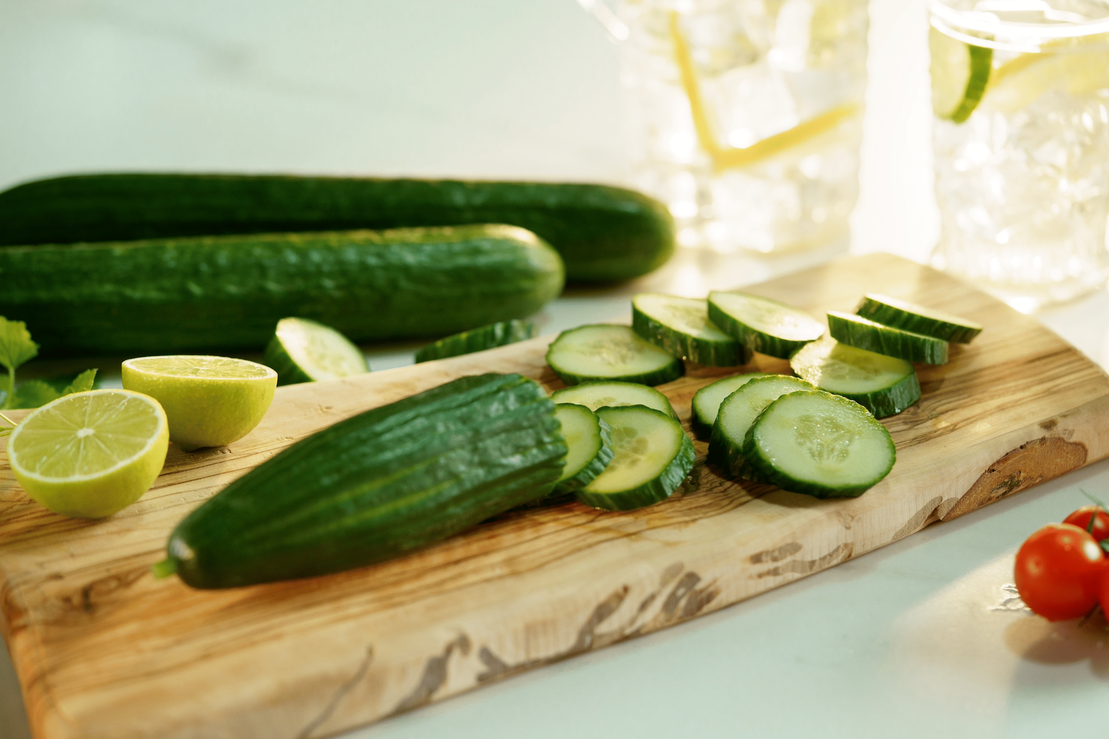 A wooden cutting board with slices of cucumber, a hydrating food.