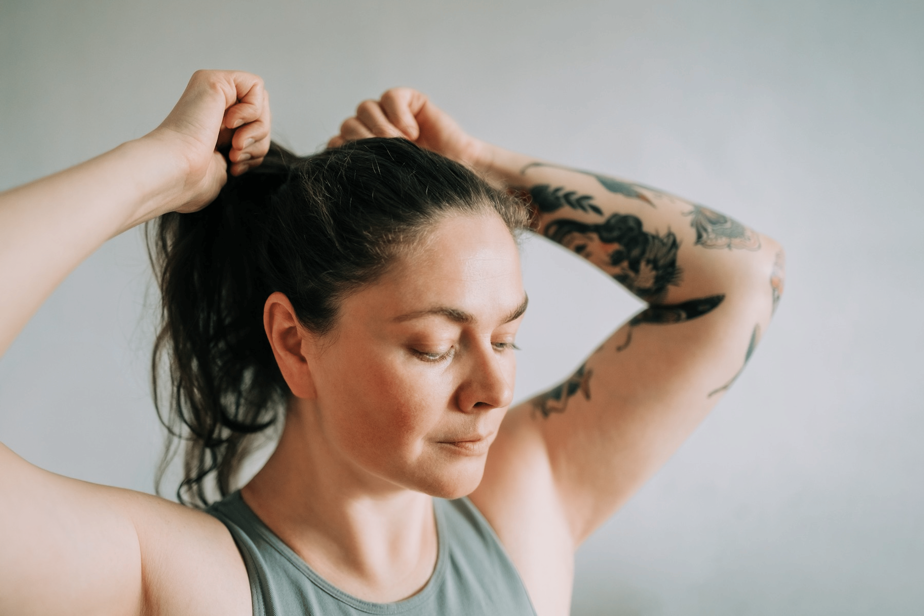A woman tying her hair into a ponytail before a workout.