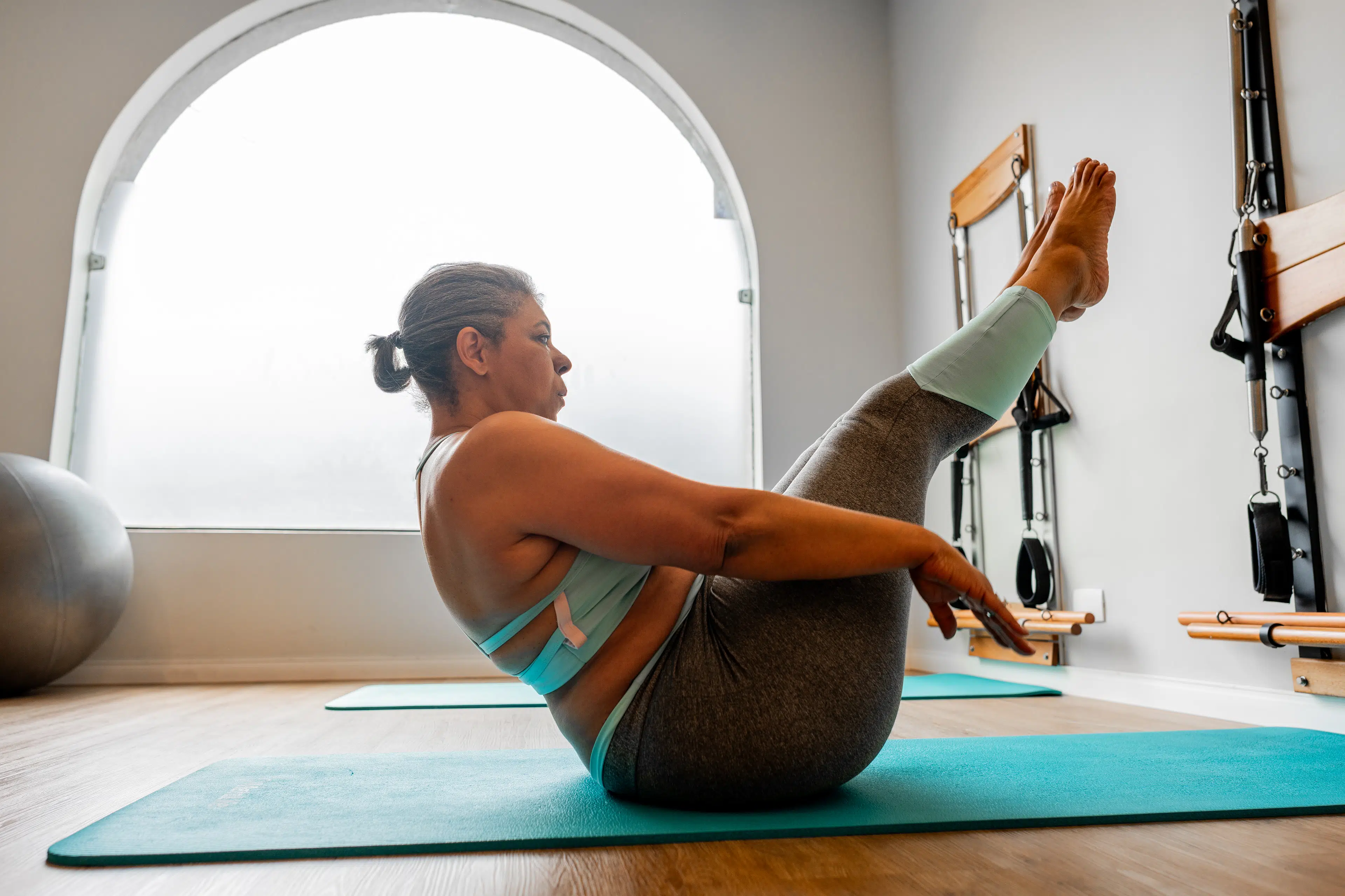 Woman doing teaser in a Pilates workout on an exercise mat