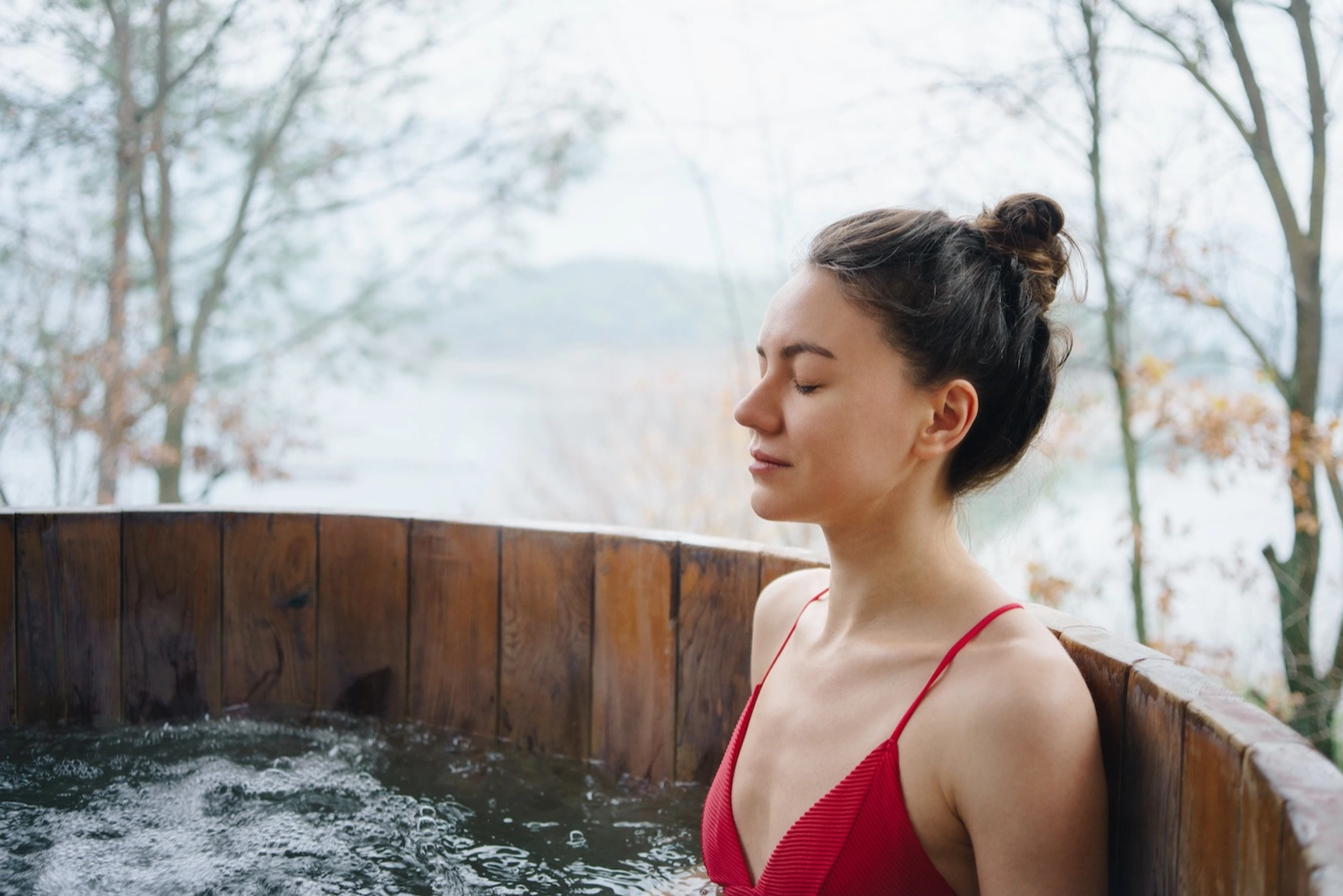 A woman closing her eyes while taking a cold plunge before or after a workout.