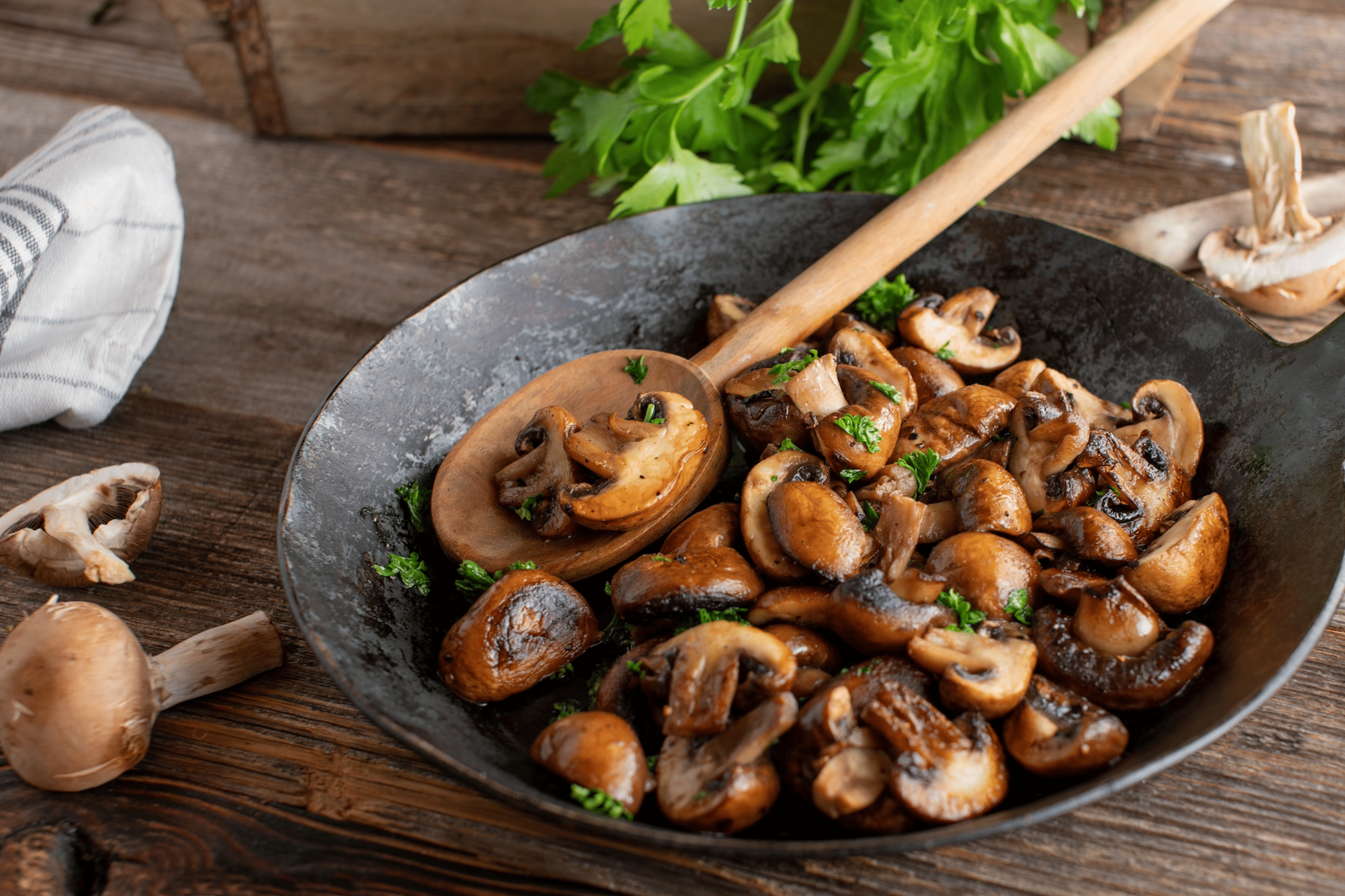 A bowl of pan-friend mushrooms sitting on a table. Mushrooms are high-protein vegetables.