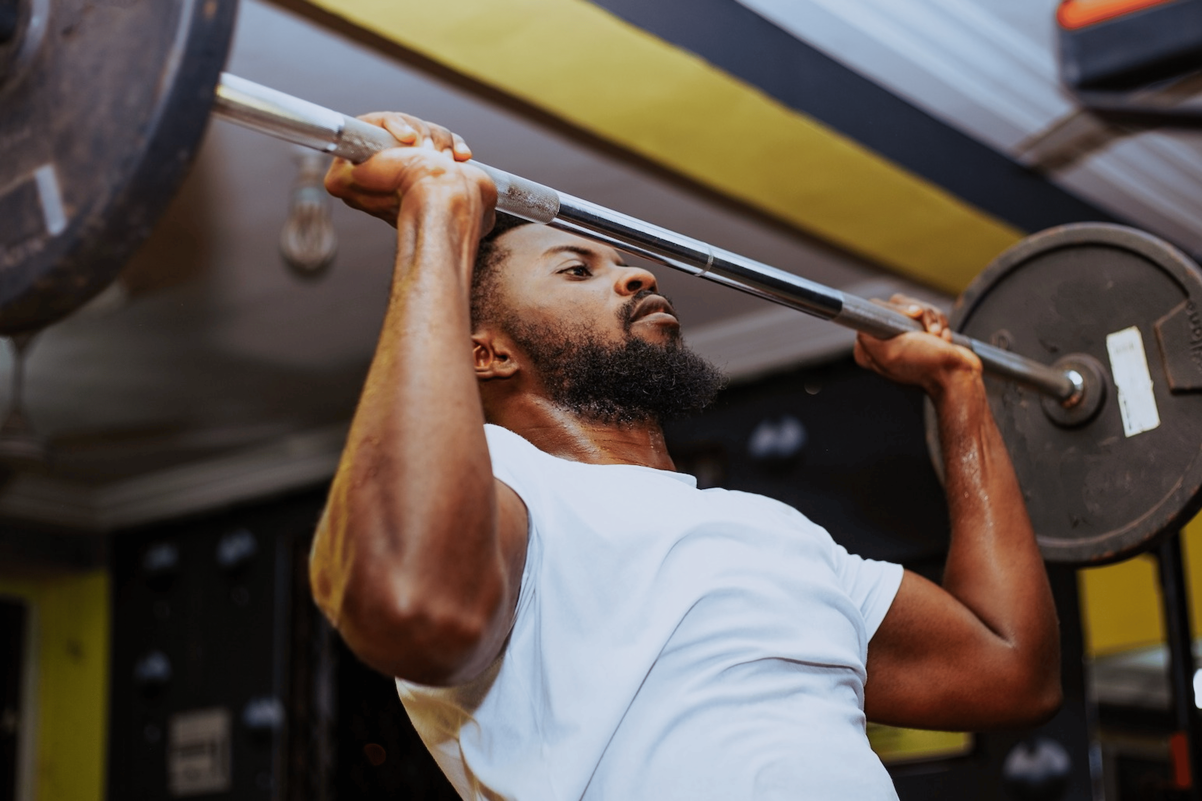 A man lifting a barbell at the gym.