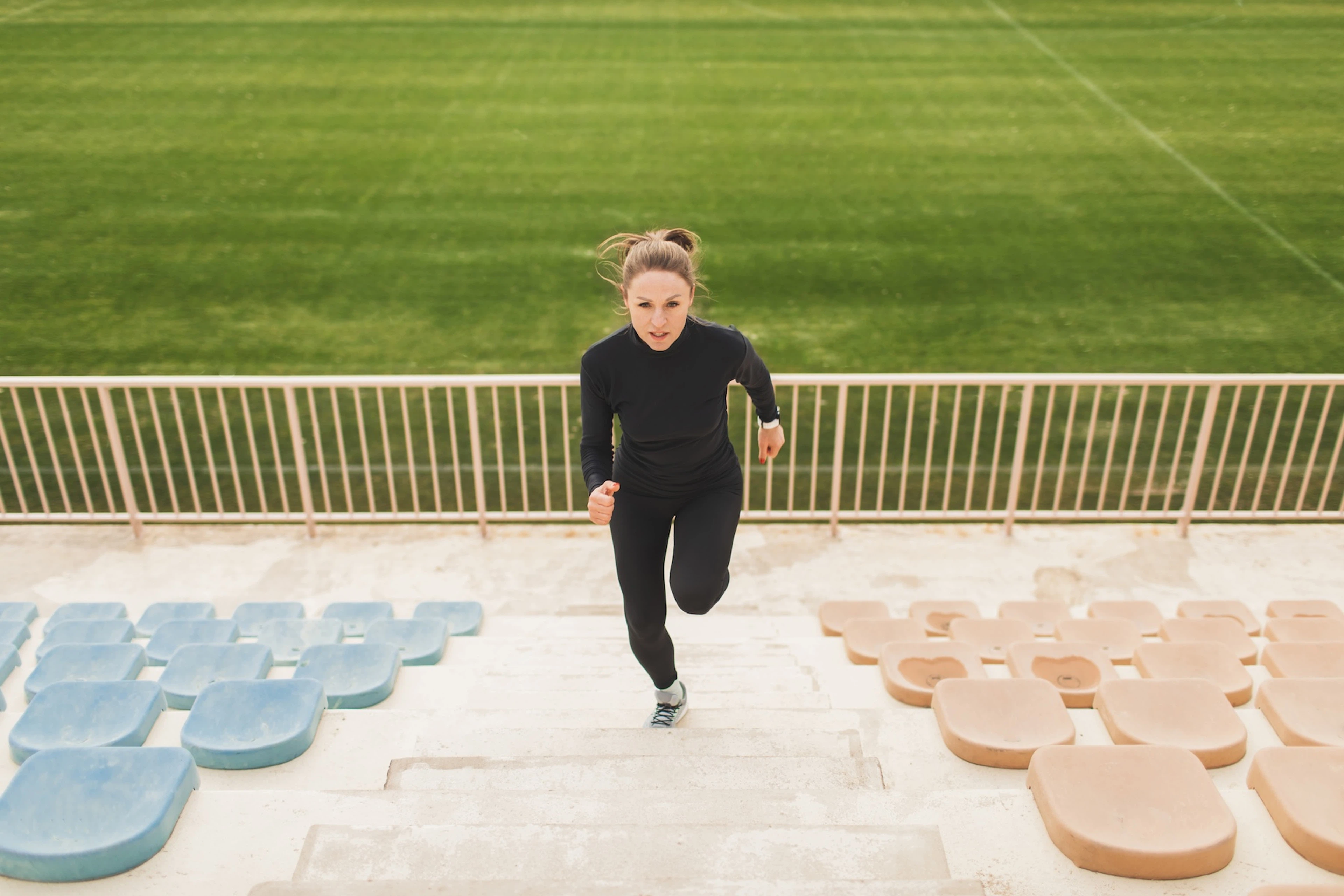 A woman running up a flight of stairs at an outdoor stadium.