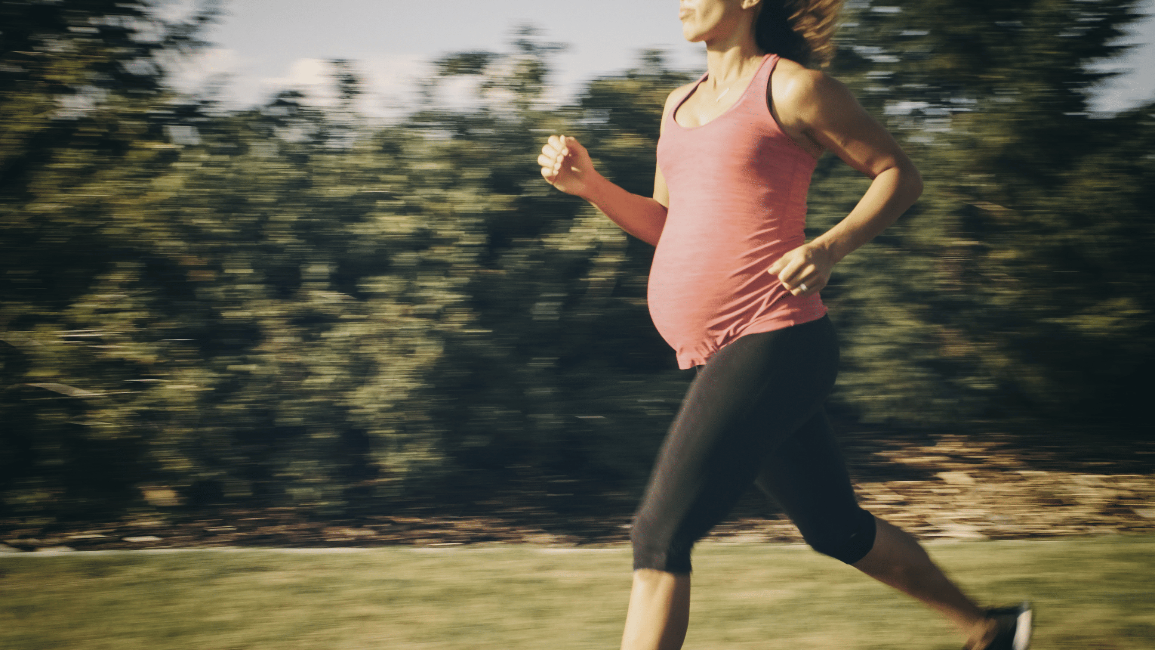 Woman running while pregnant outside 