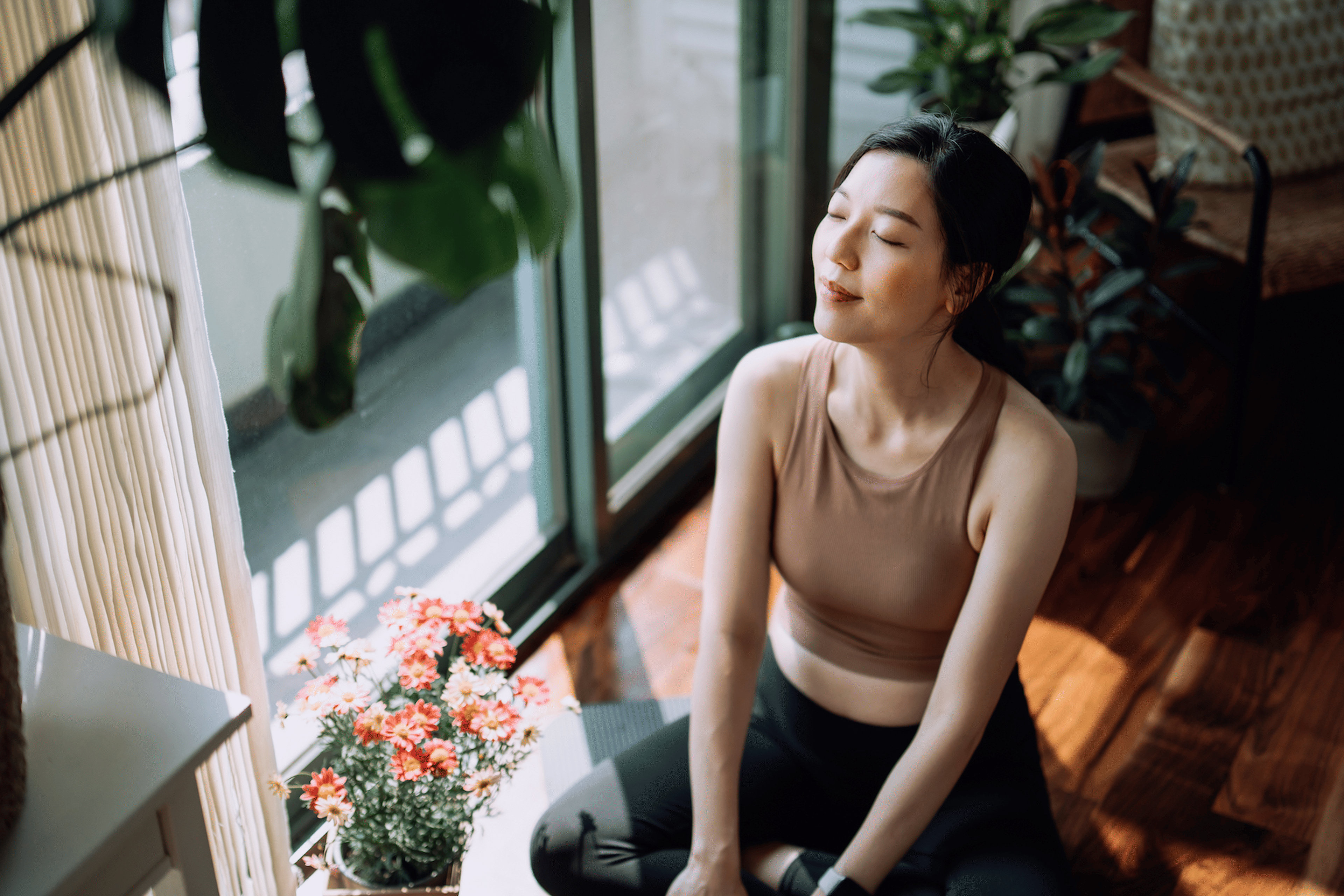 A young woman sitting at home in a sunny room and practicing a meditation for anxiety.