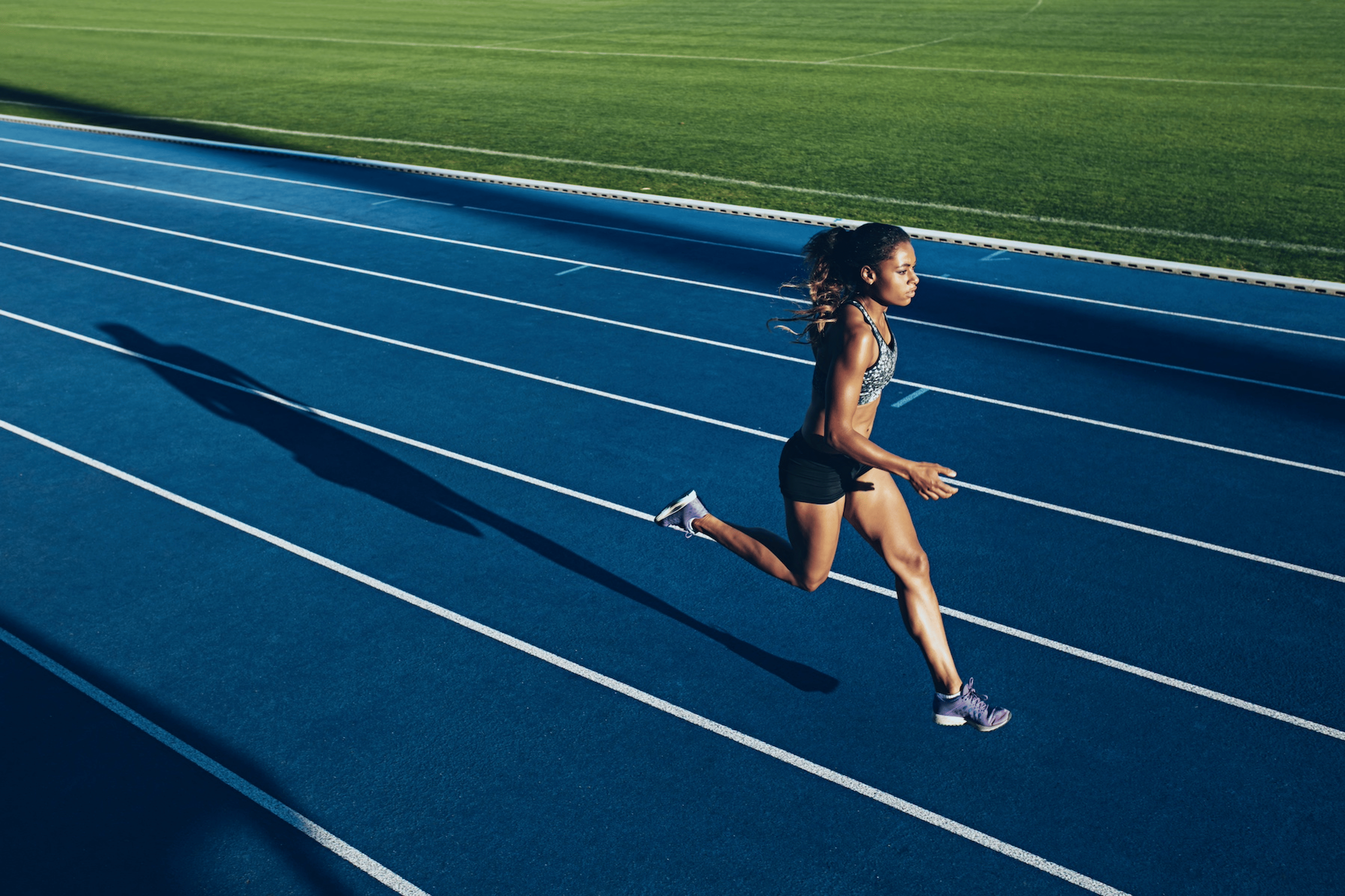 A woman running fast on a track, using her rate of perceived exertion to guide her efforts.
