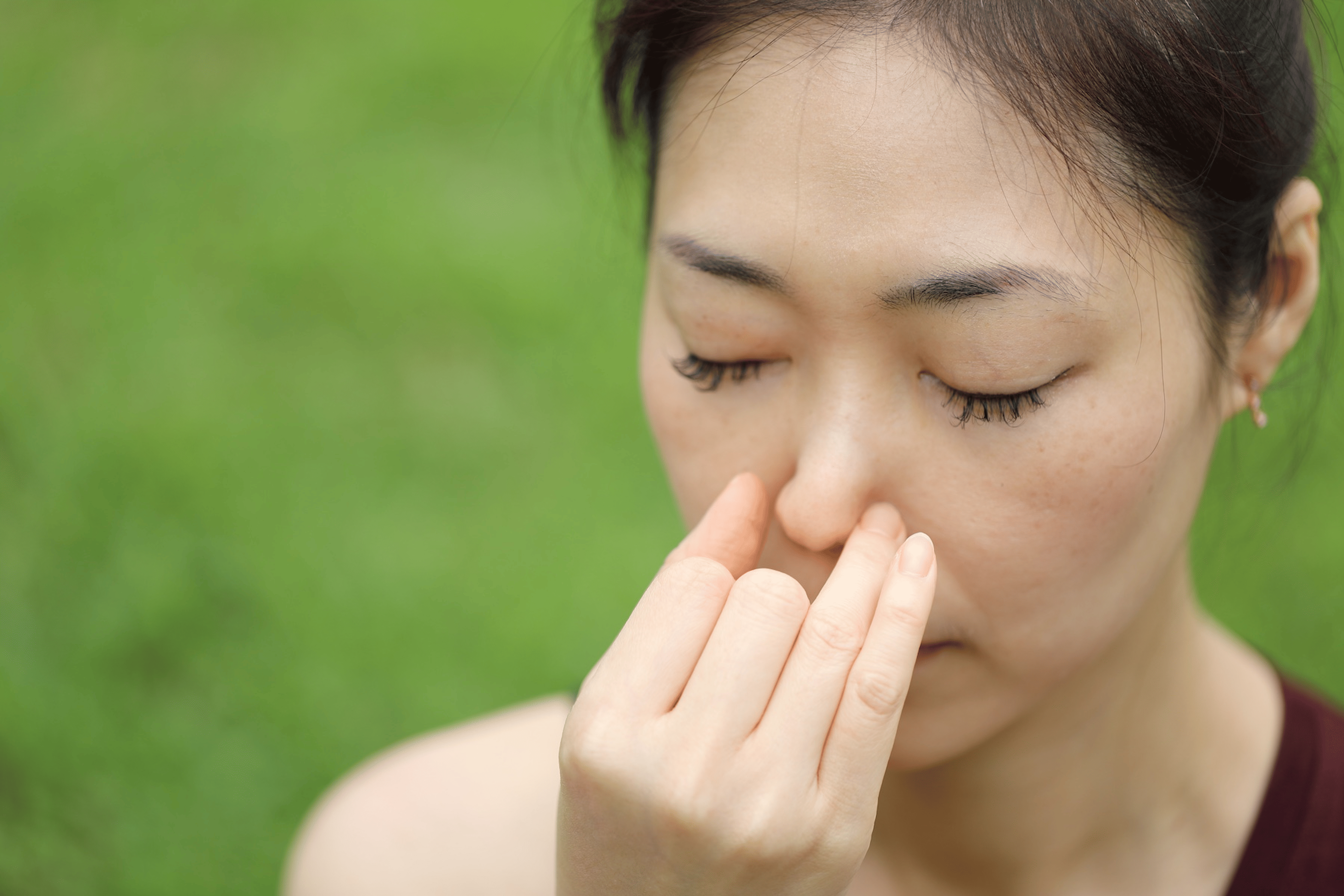A woman making a mudra with her right hand while practicing alternate nostril breathing.