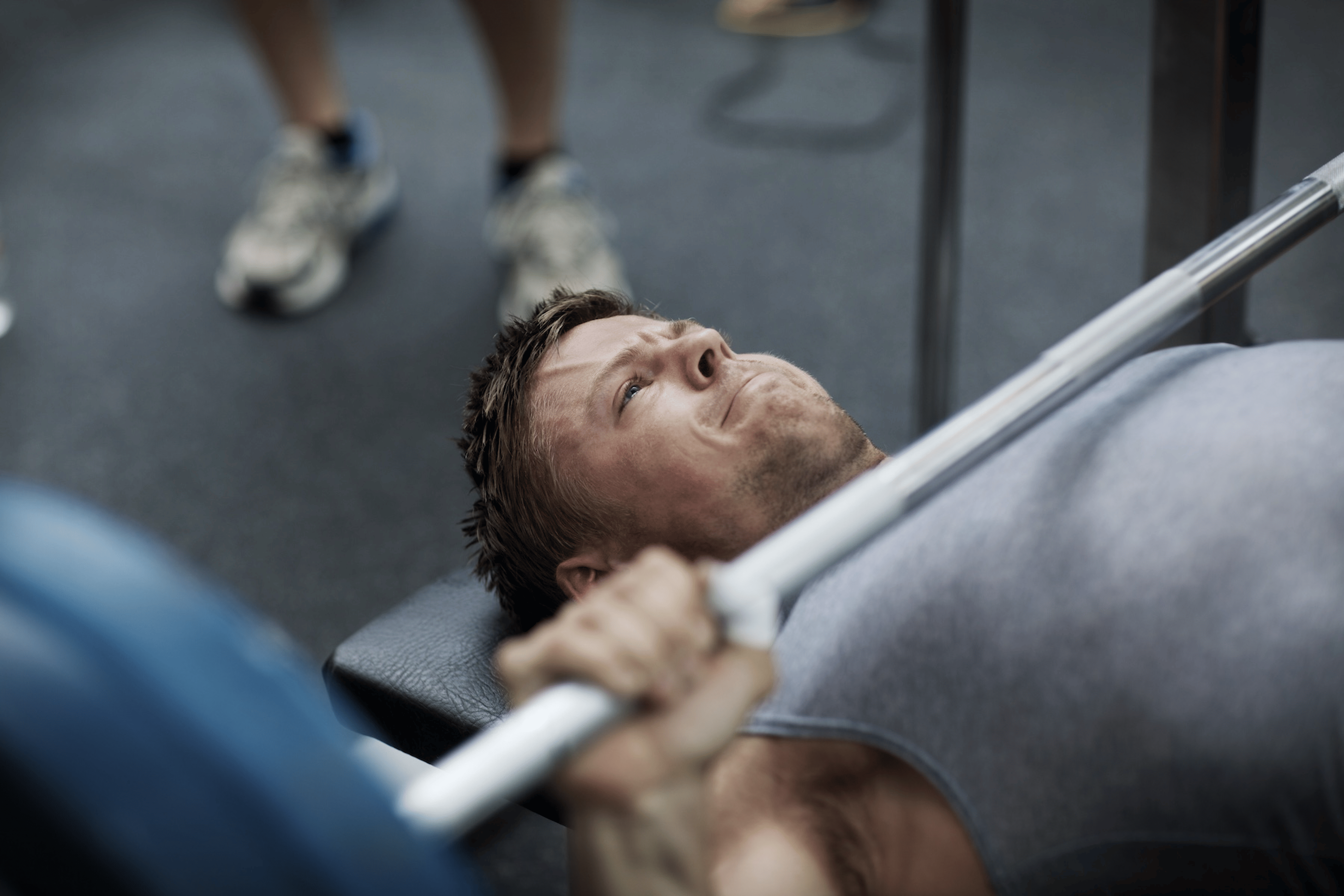 A man about to perform a bench press at the gym with a barbell. He is holding his breath.
