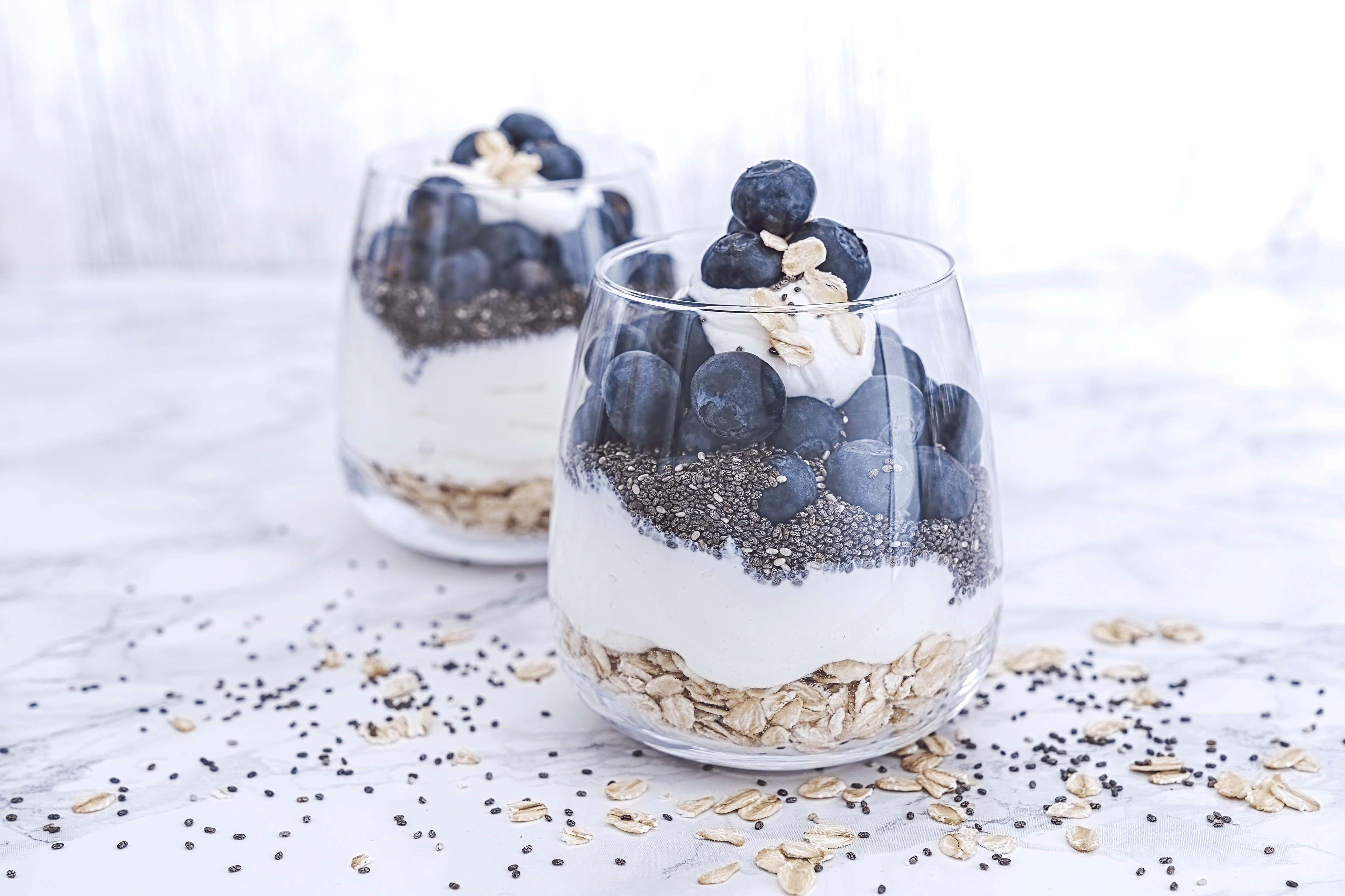 Two glasses with quark, oatmeal, chia seeds, and blueberries