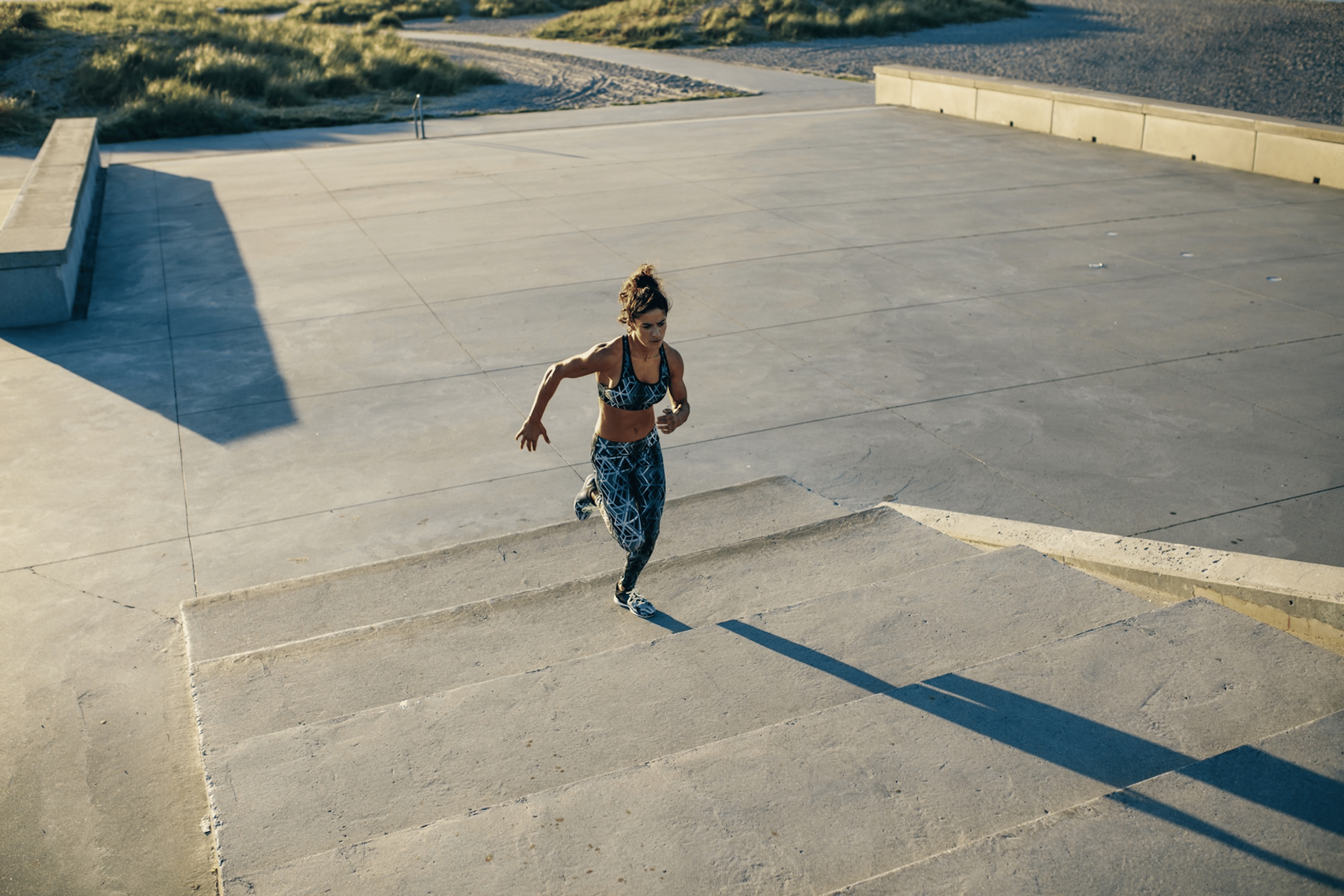 A woman doing an interval workout on a set of outdoor stairs. Complex carbs can help fuel your body for workouts.