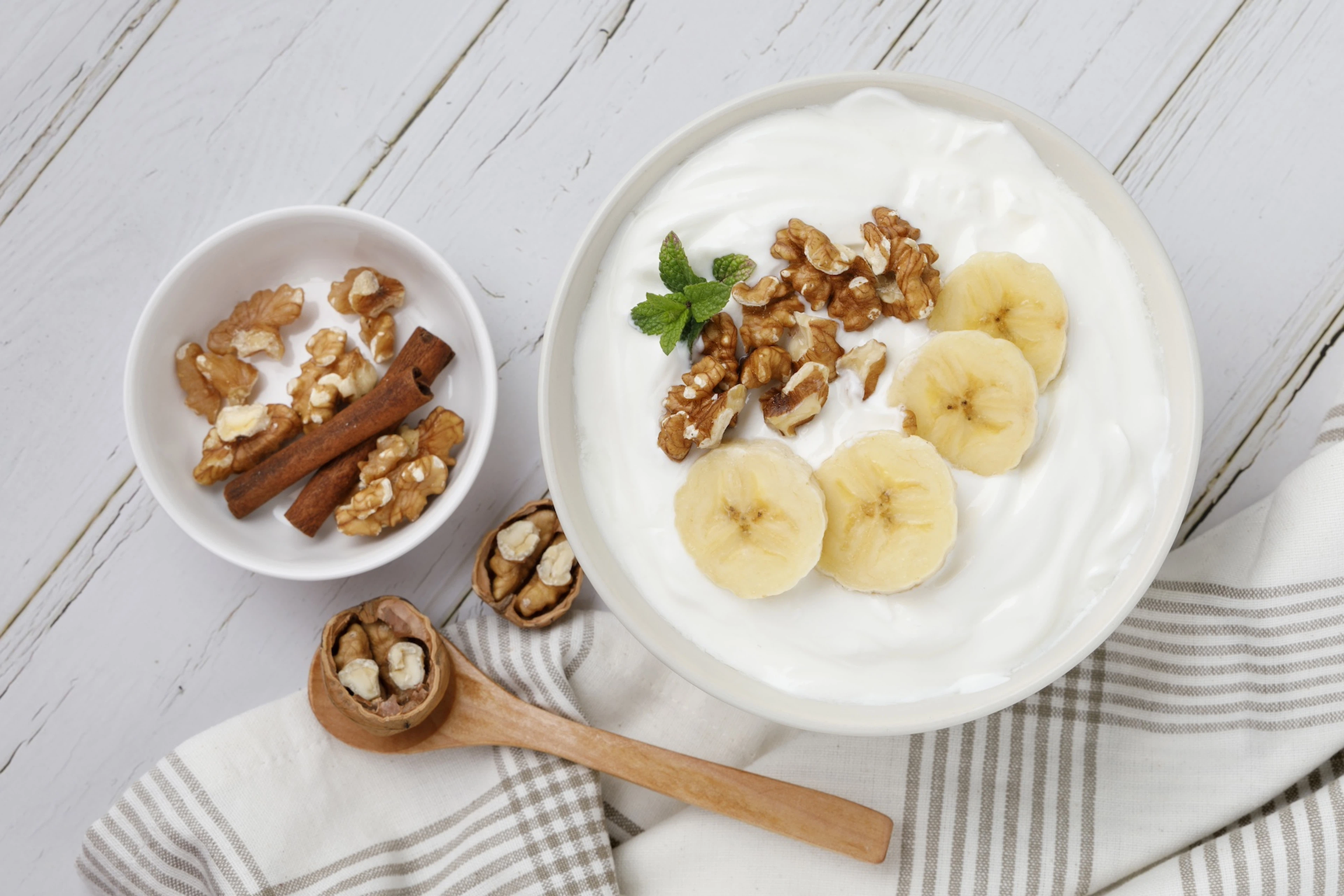 A bowl of Greek yogurt with banana and walnuts.