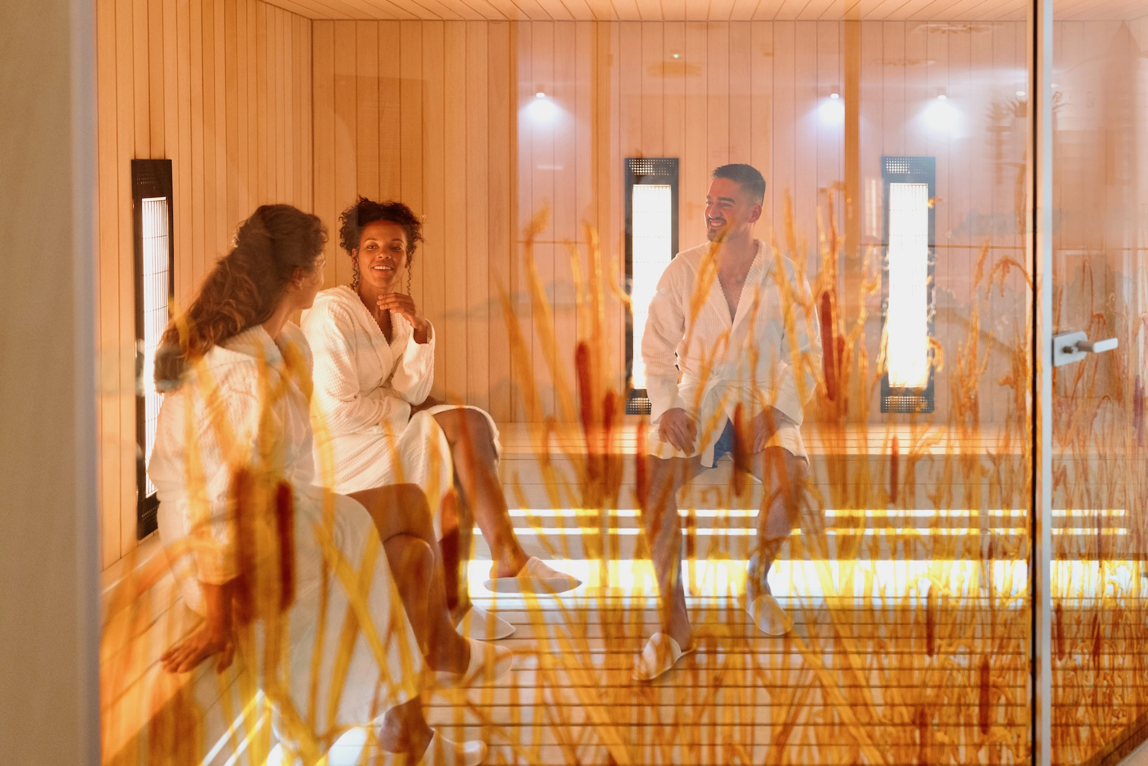 A group of three friends relaxing in an infrared sauna. Learn about infrared sauna benefits in this article.