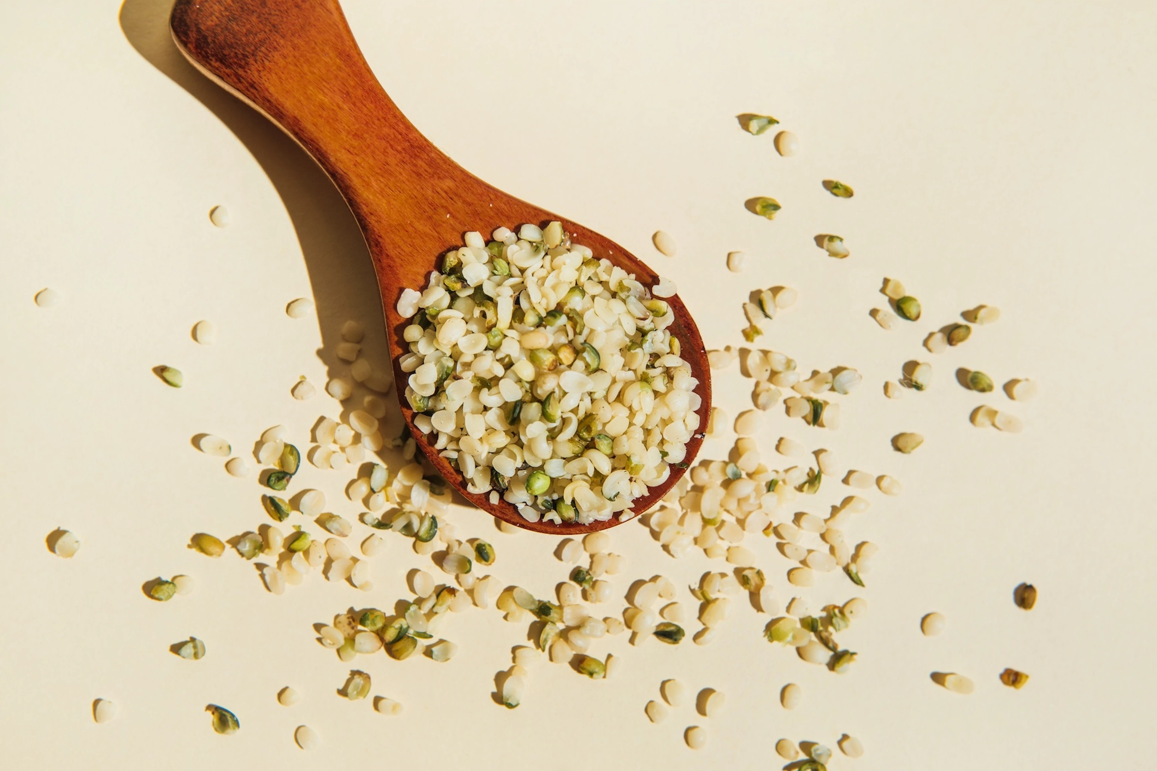 A wooden spoon spilling over with hemp seeds.