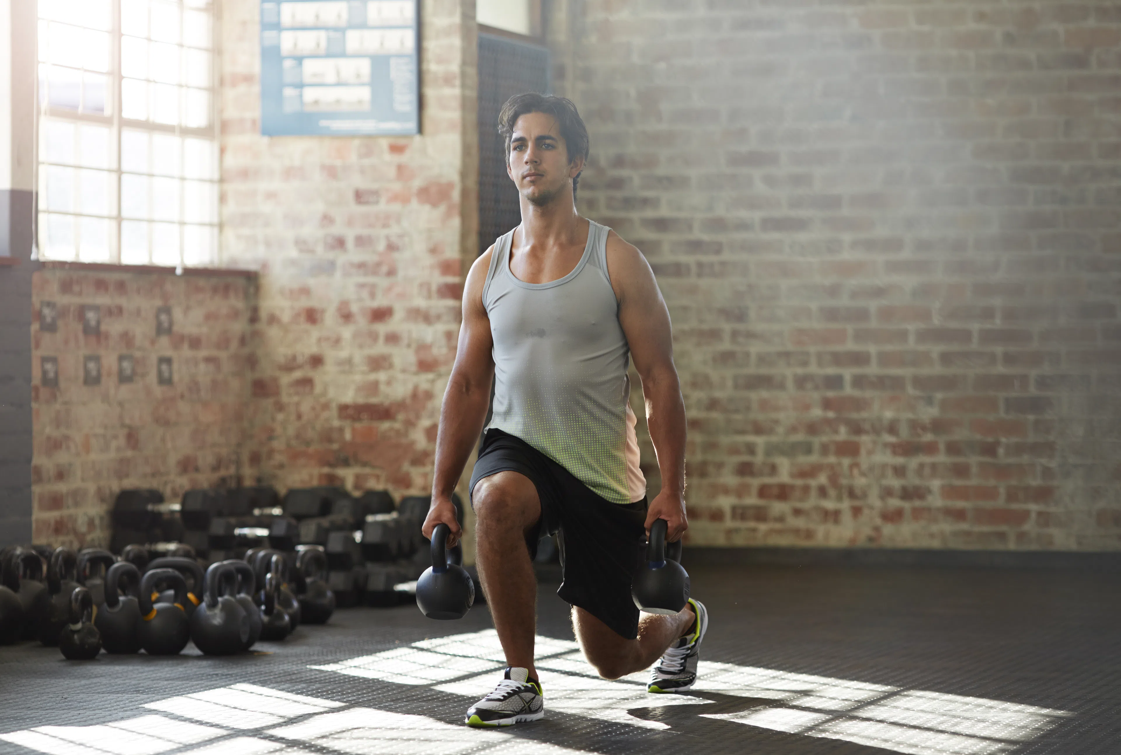 Man doing weighted lunge in gym
