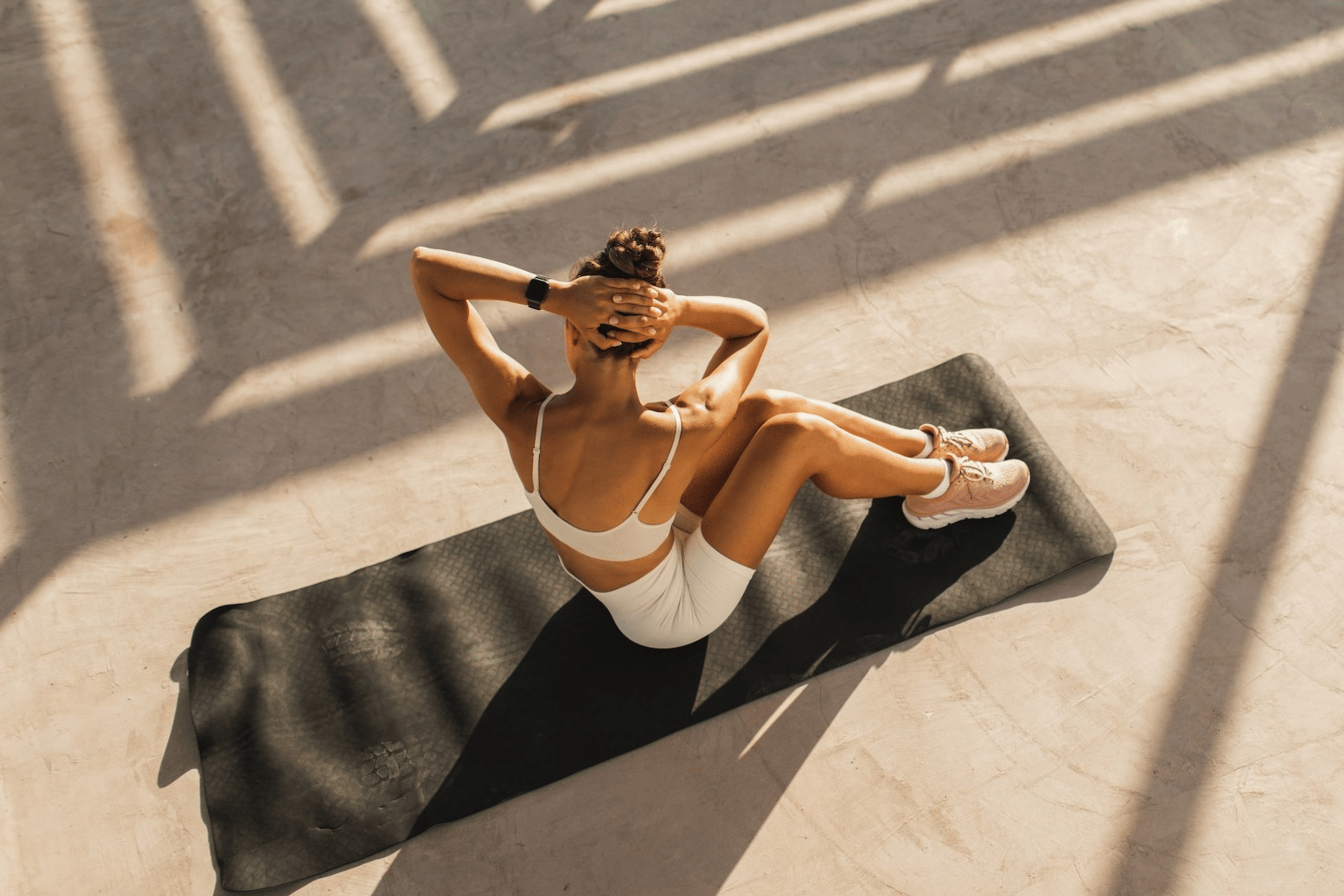 A woman doing a core workout while sitting on a yoga mat outside.