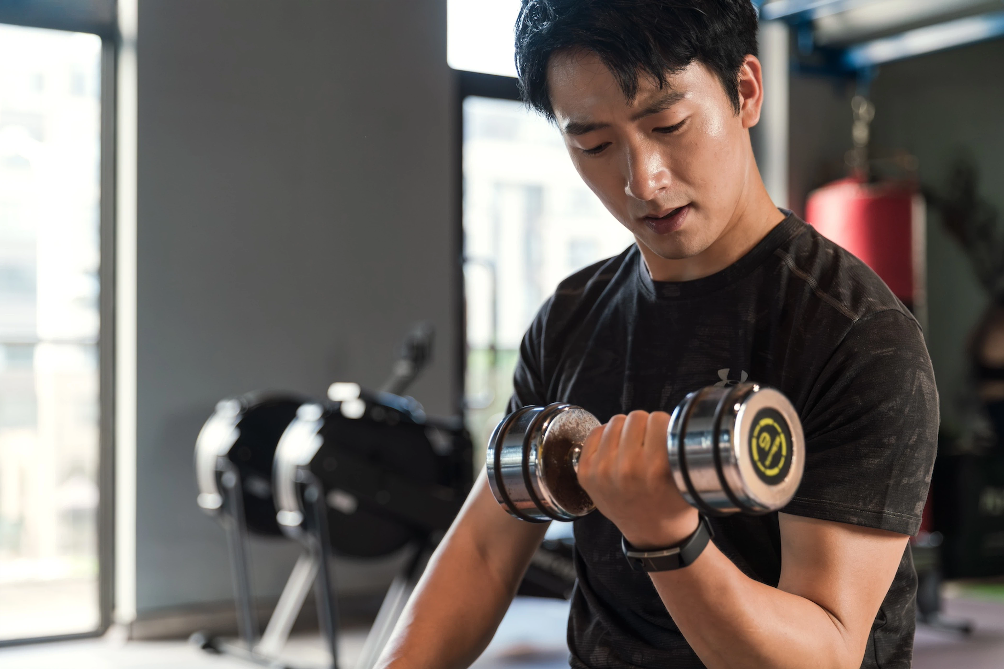 A man lifting a dumbbell in a gym, using his rate of perceived exertion to gauge his effort.