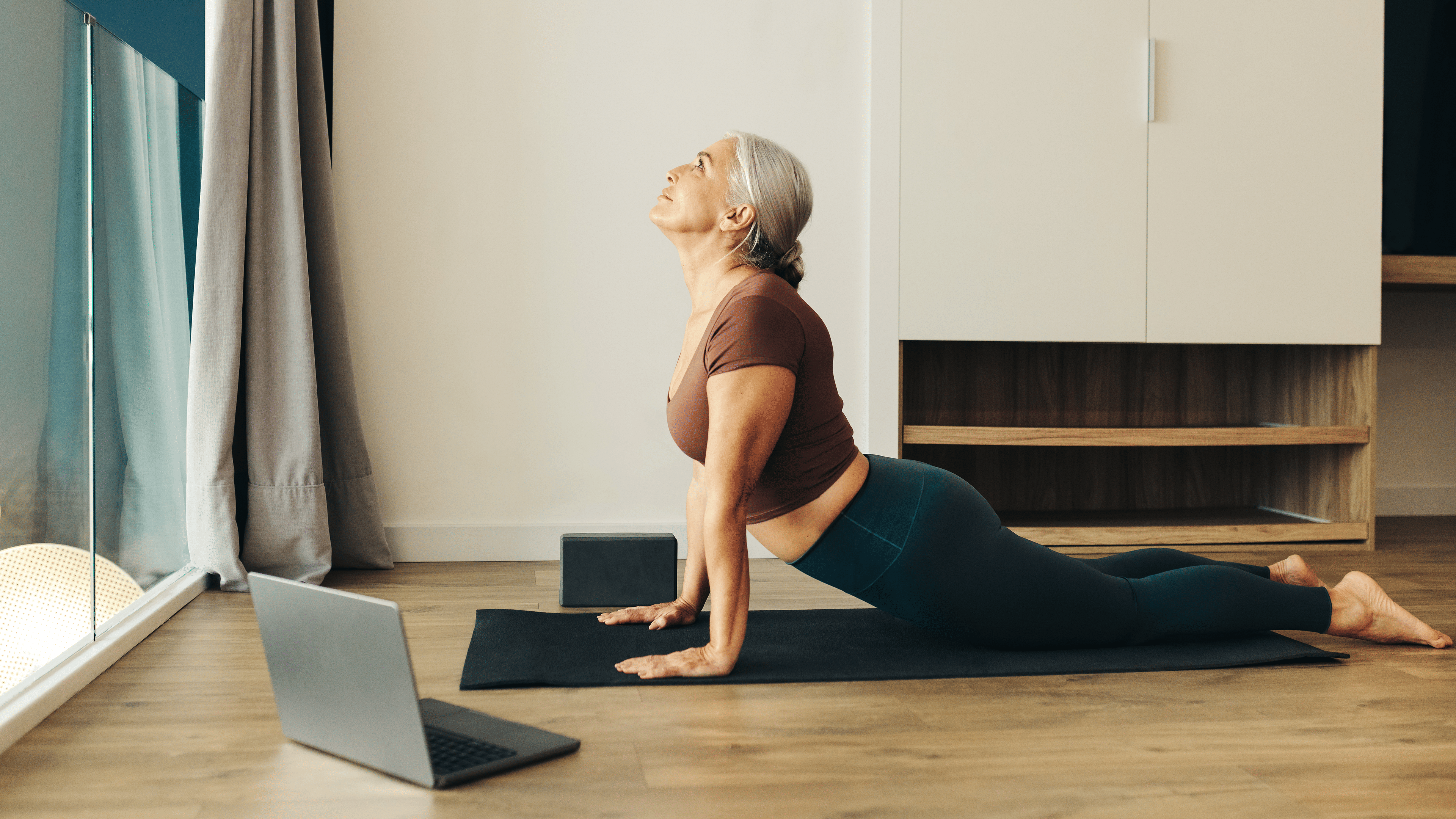 Woman practices Upward-Facing Dog pose on her yoga mat at home