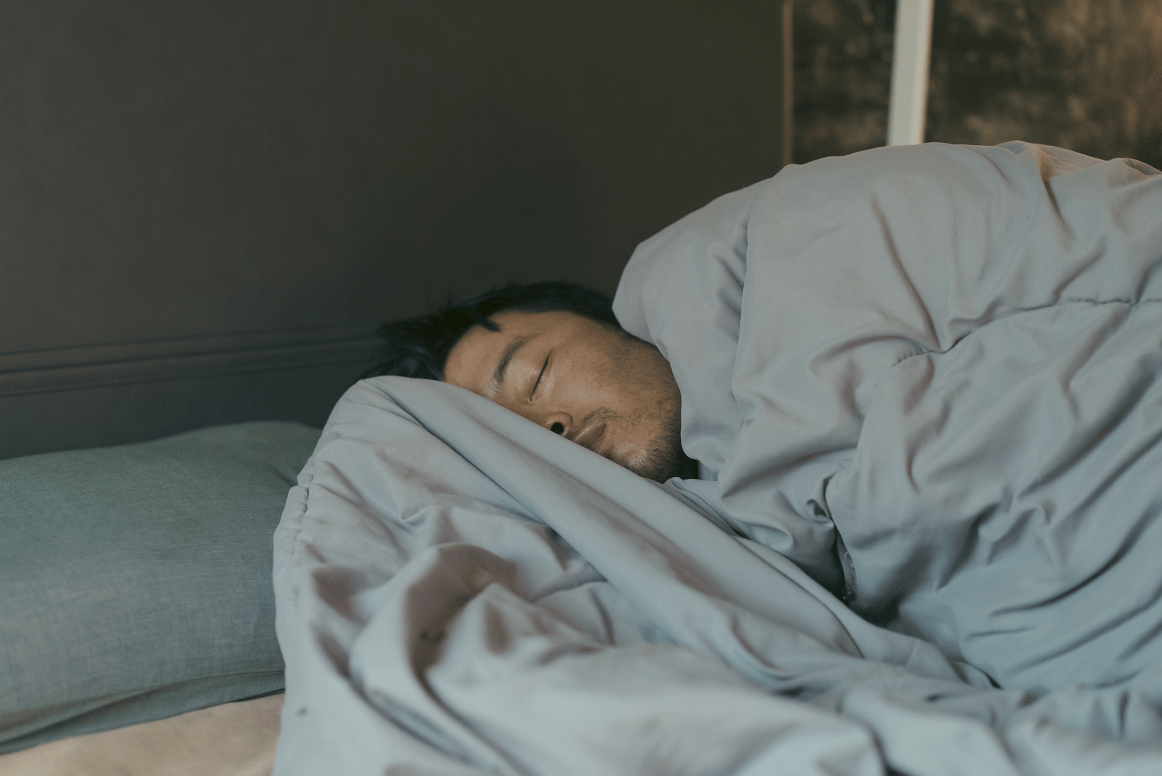 A man sleeping soundly in bed at the best temperature for sleep.