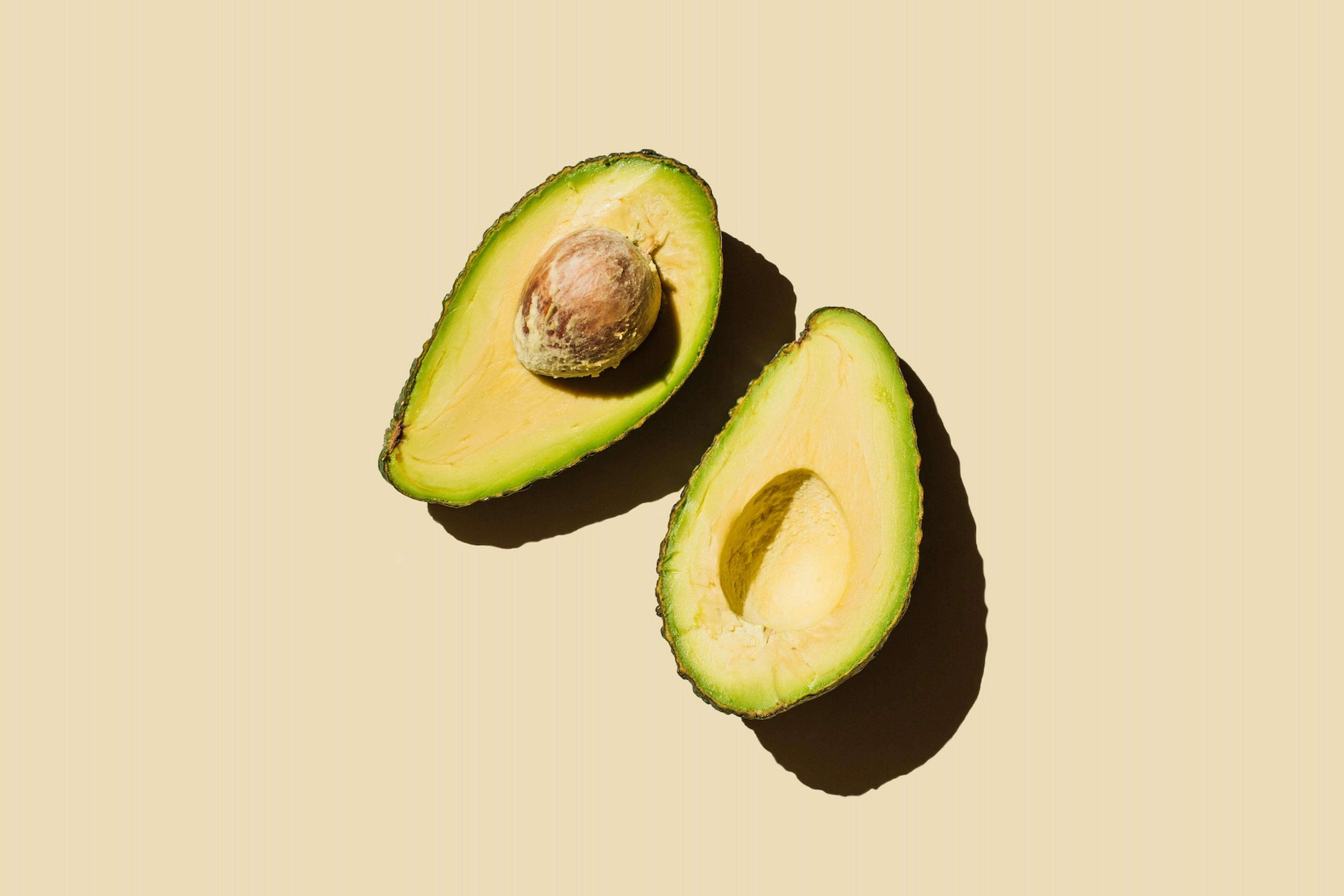 An avocado (which is a high-protein fruit) sliced in half with both halves facing upright.