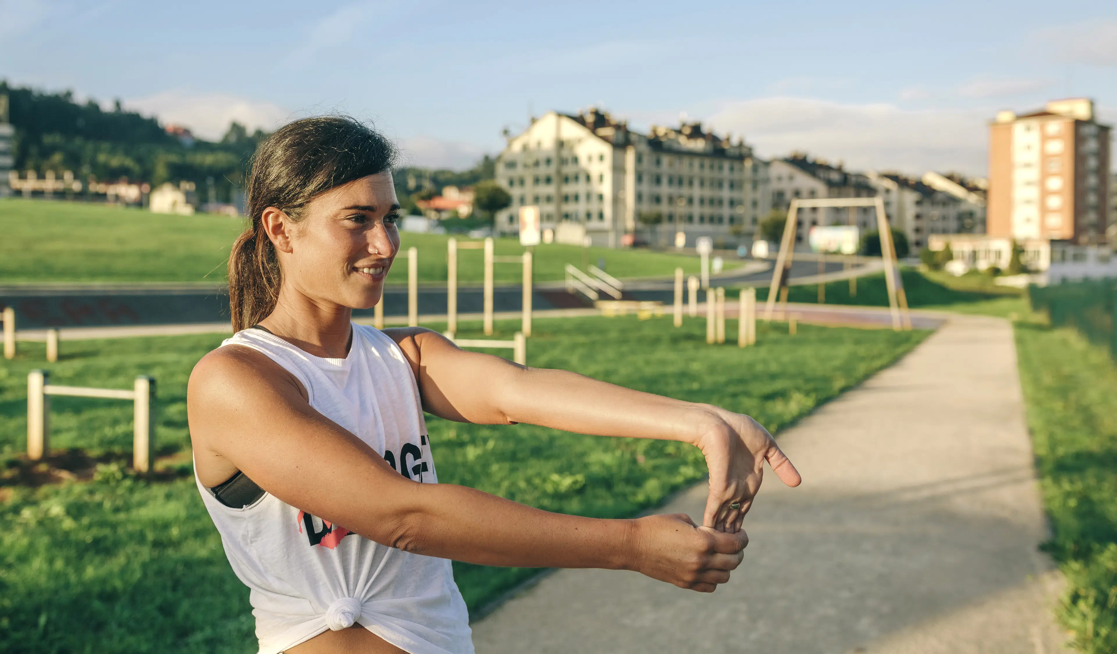 Woman does a wrist flexion  stretch outdoors