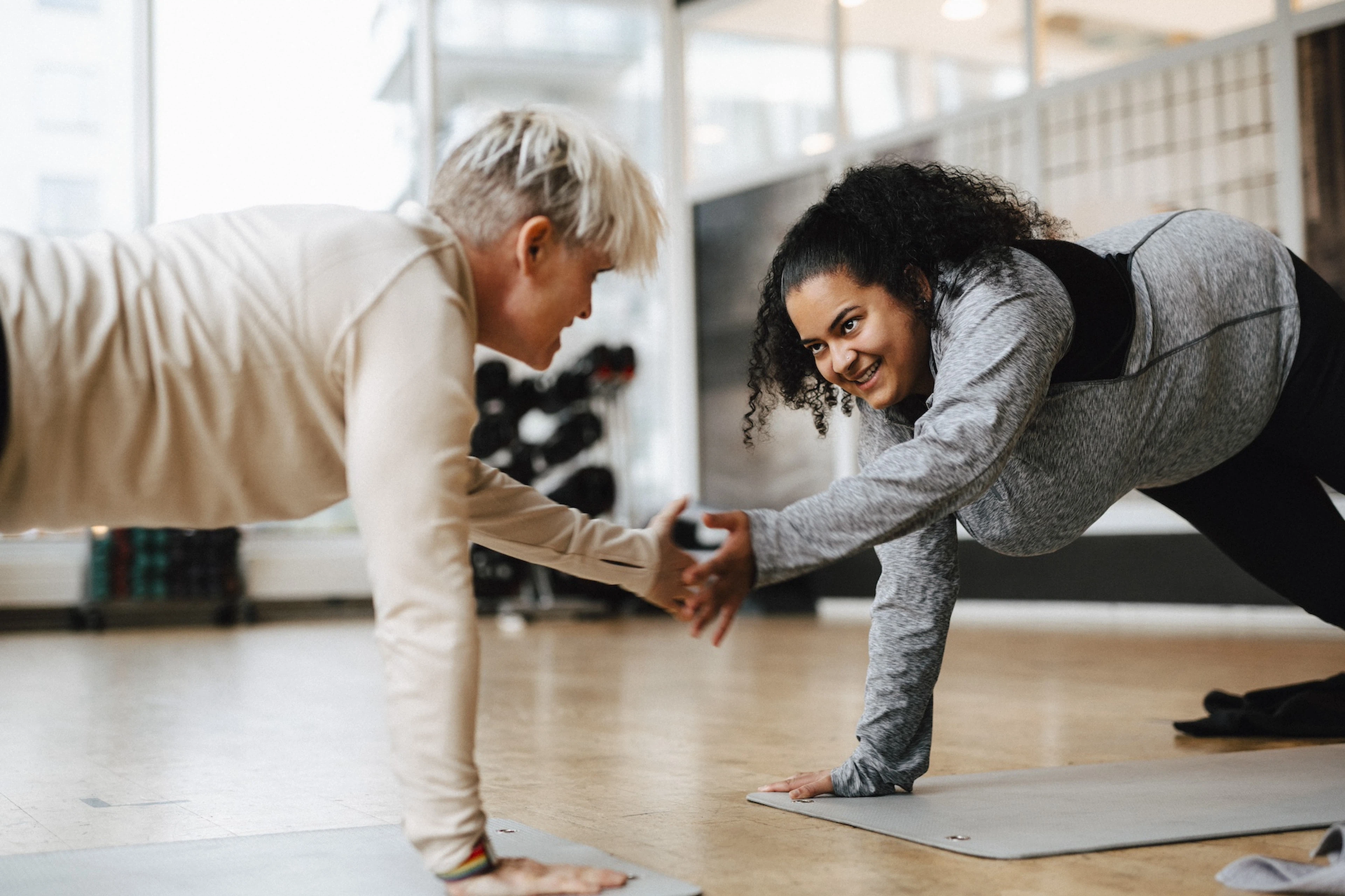 Two people engaging in friendly competition, exercising together and giving each other a high-five while in a plank position on exercise mats.