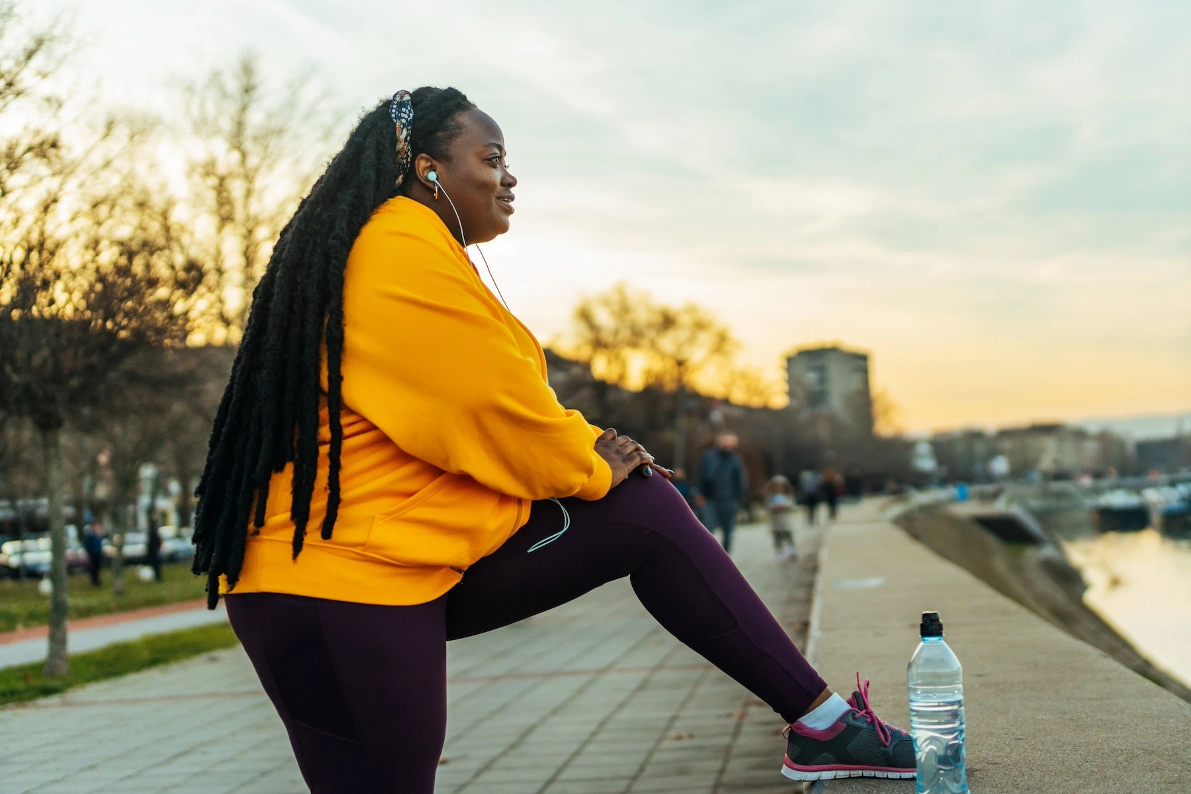 A woman happily stretching her legs outside before exercising.