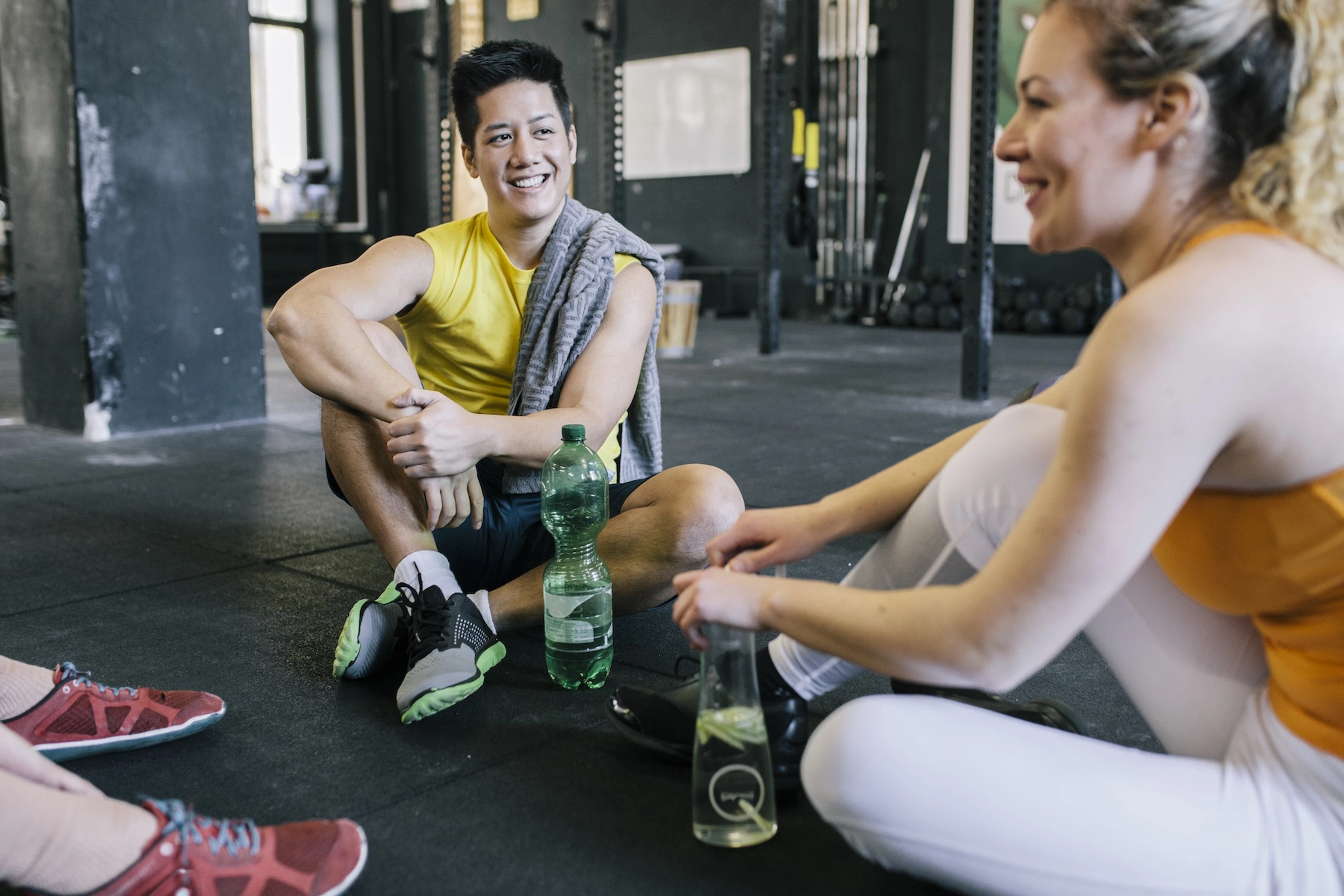 Two friends sitting down at the gym and talking, practicing social wellness.