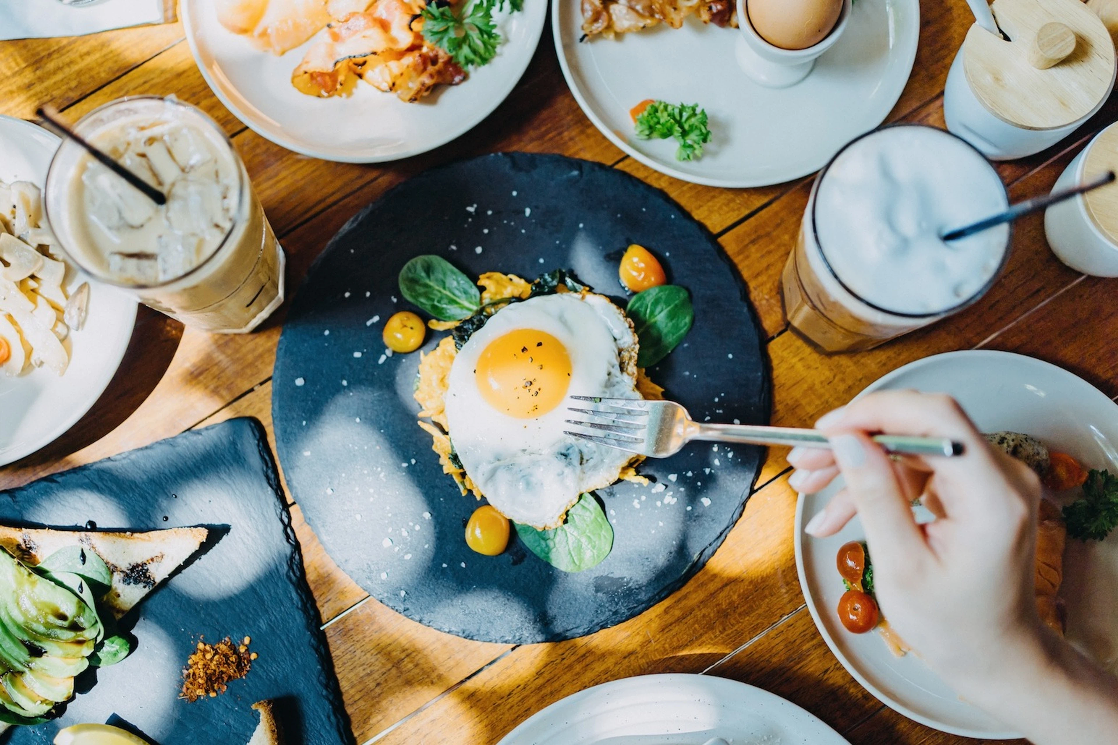 Birds-eye view of someone eating a sunny-side-up egg (a complete protein) at an outdoor restaurant.