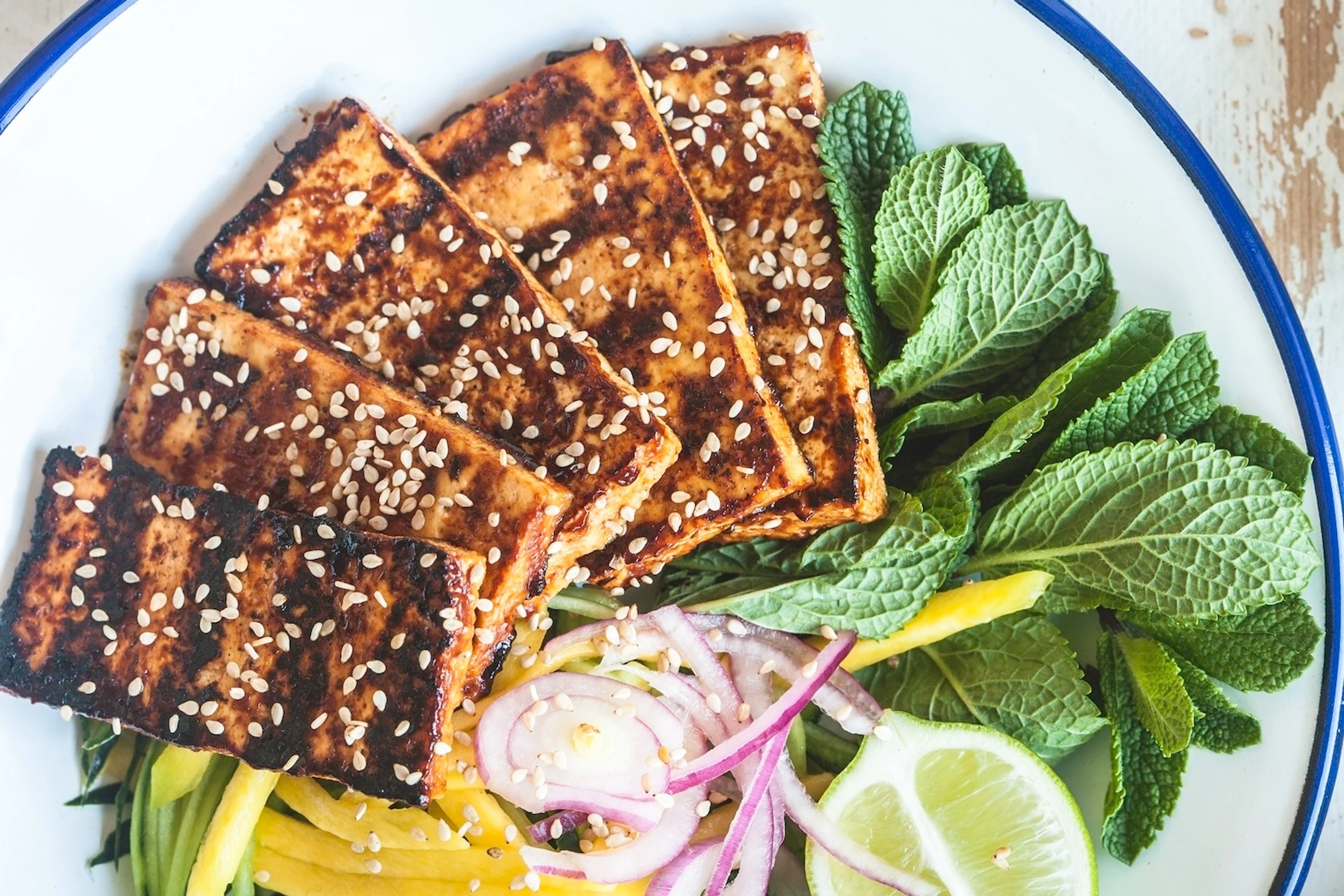 Tofu cutlets on a plate with assorted fruits and veggies.