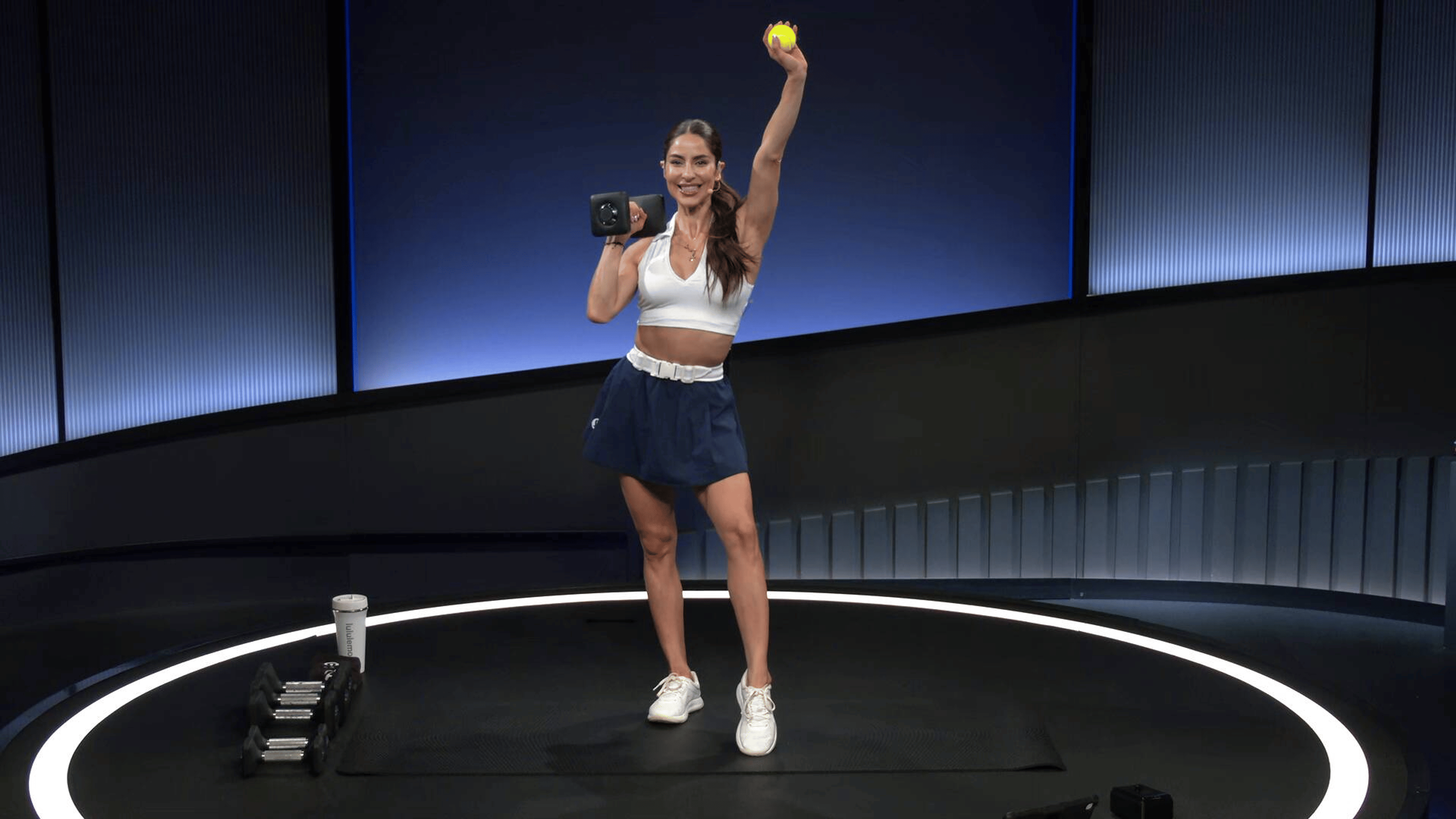 Peloton instructor Assal Arian poses with a dumbbell and tennis ball during a Peloton strength for tennis class.