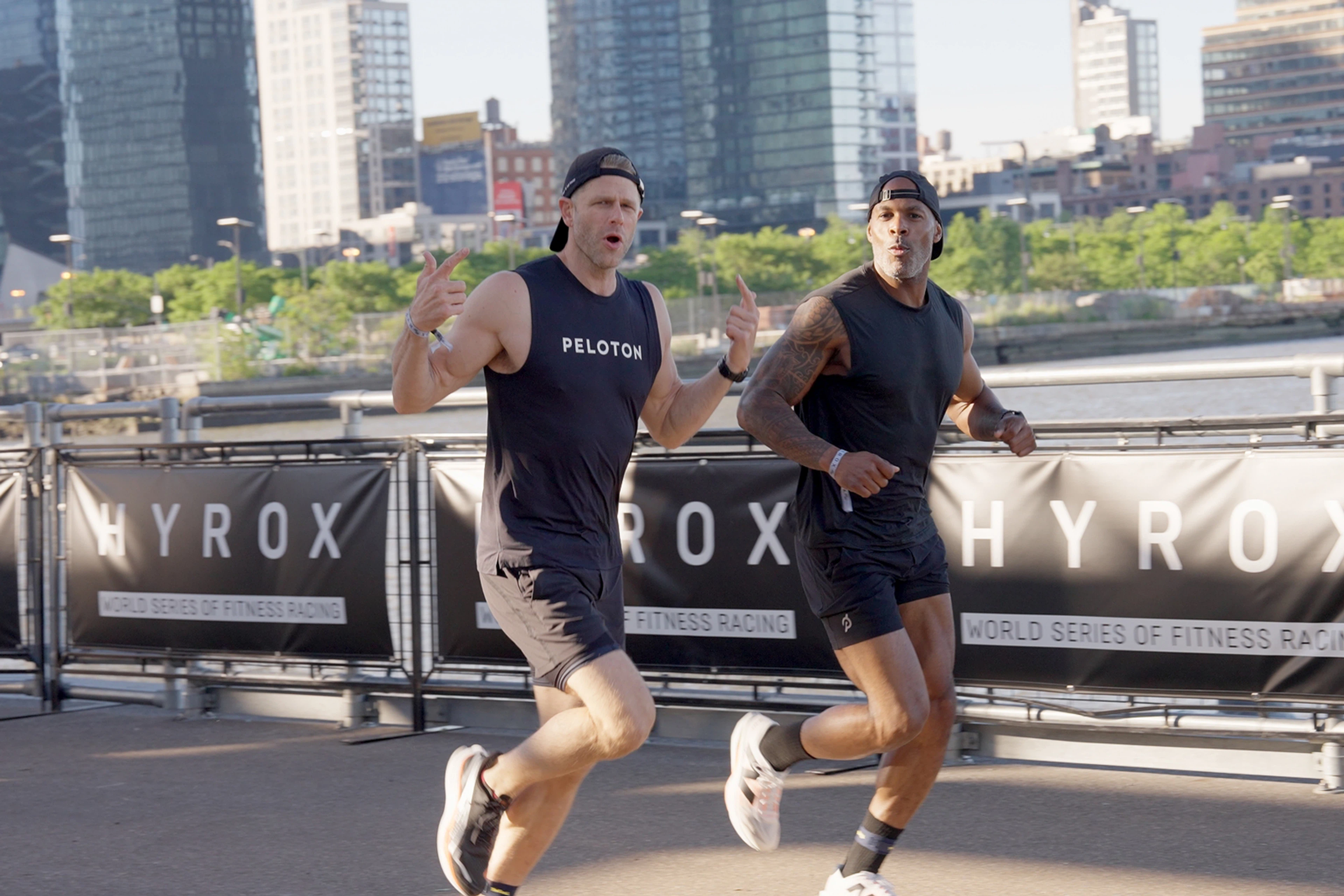 Peloton instructors Andy Speer and Adrian Williams running during a HYROX race.