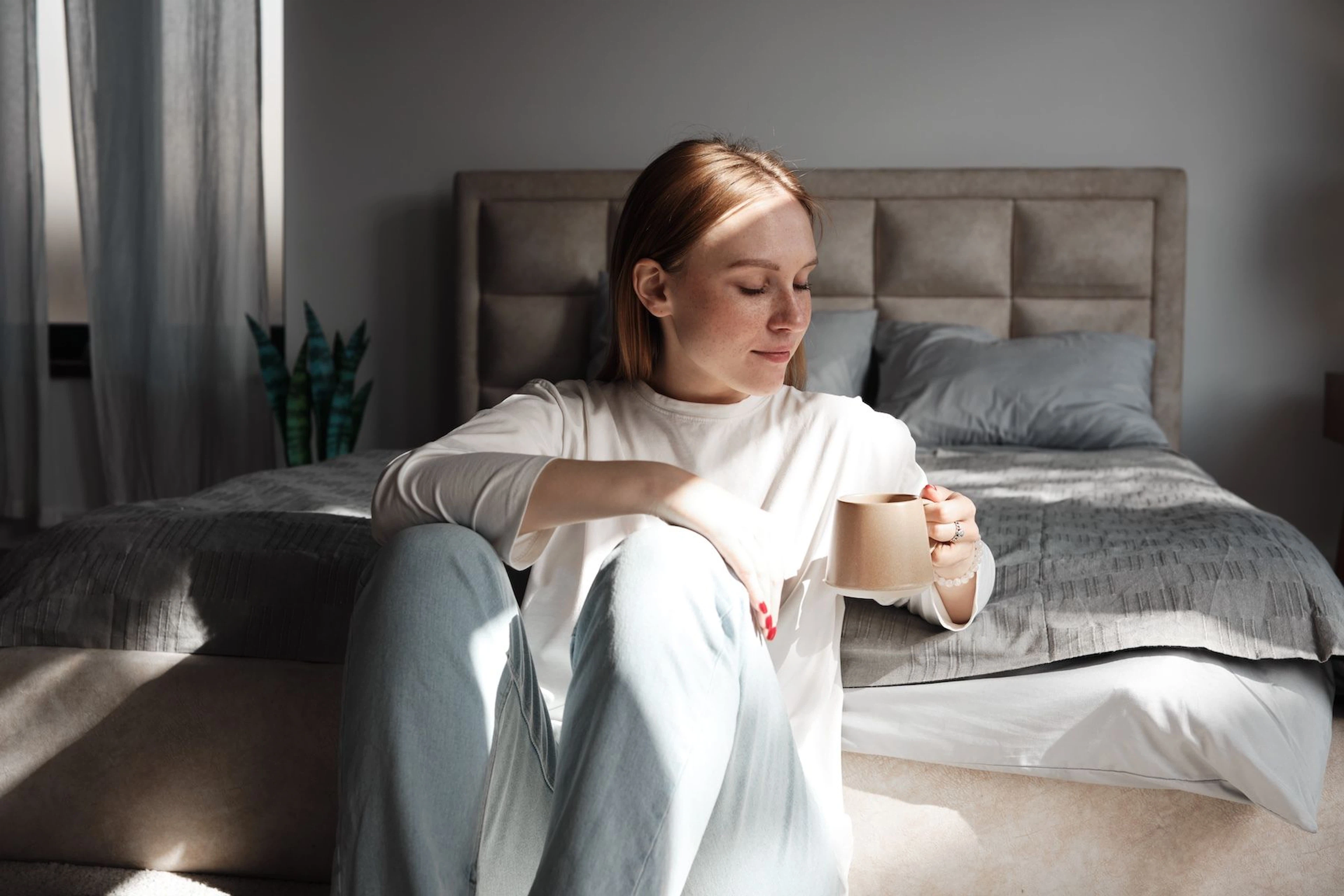 Woman with coffee in bedroom
