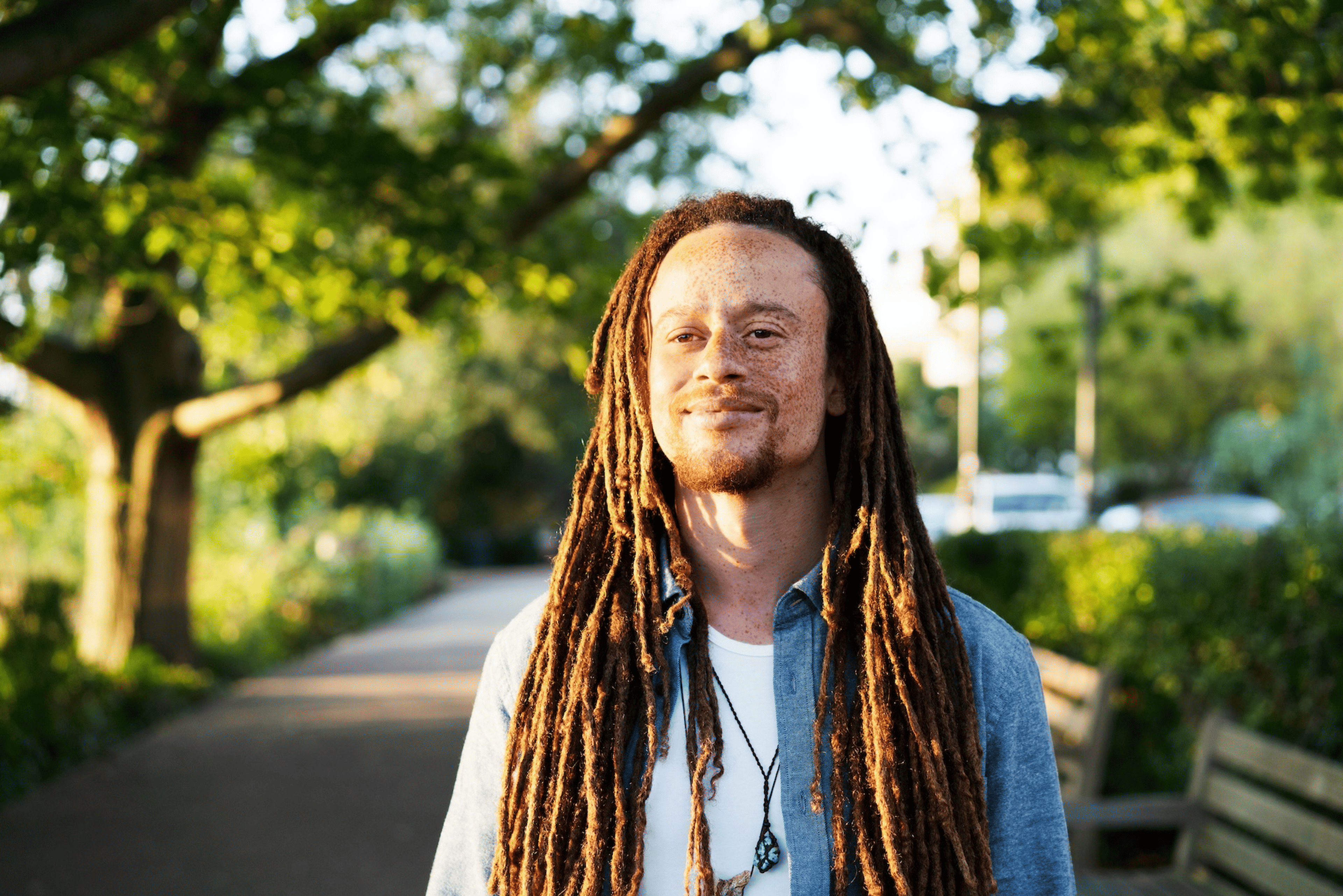 A man doing a walking meditation through a park on a sunny day.